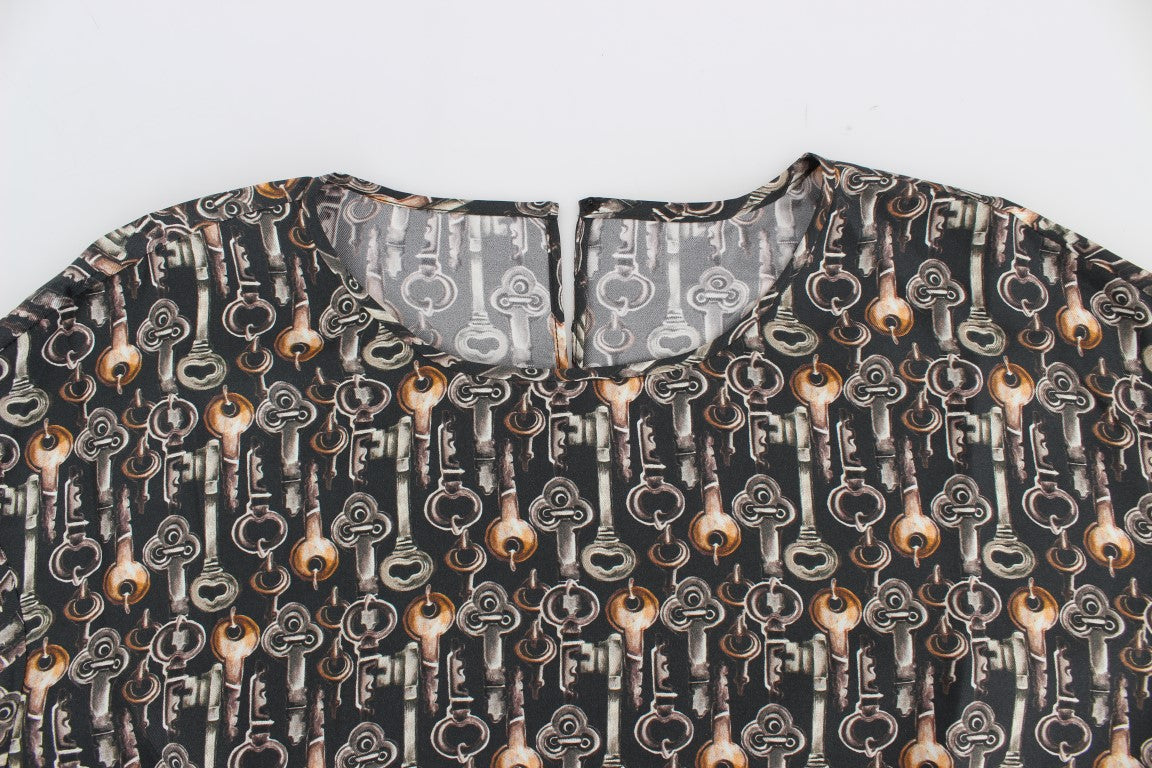 Chemise en soie Dolce & Gabbana gris or avec motif clé, style blouse ou t-shirt élégant, visible en gros plan.