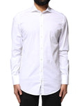 Chemise longue Dolce & Gabbana blanche en coton à manches longues avec détails dorés, élégante et sophistiquée.