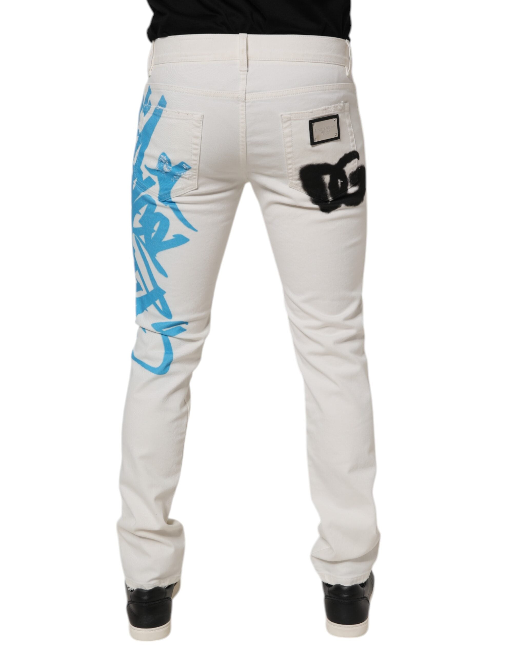 Jeans skinny en denim blanc déchiré avec graffiti, de la marque Dolce & Gabbana, affichant un style urbain et tendance.