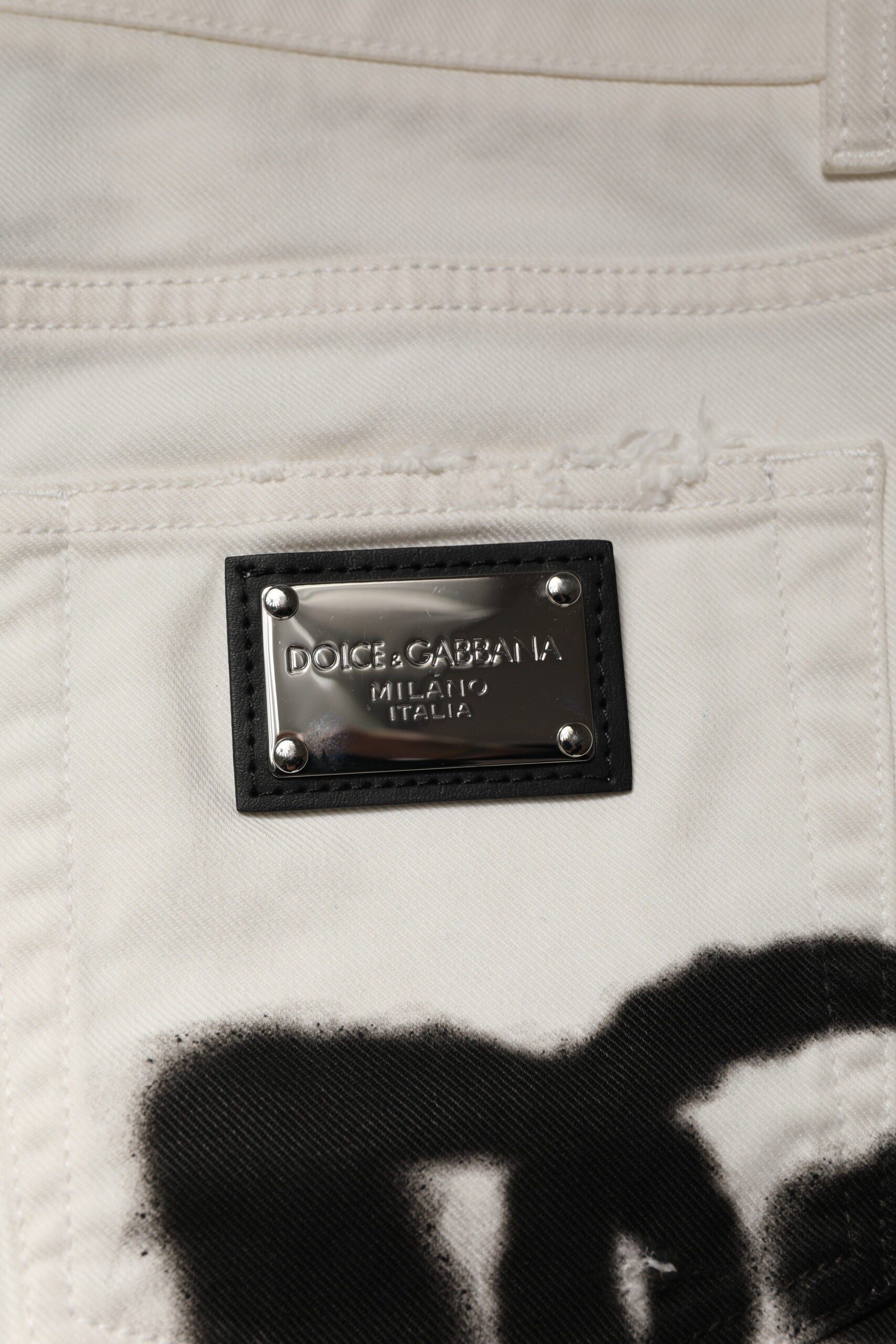 Jeans skinny en denim blanc Dolce & Gabbana avec déchirures et graffiti, style décontracté et tendance.
