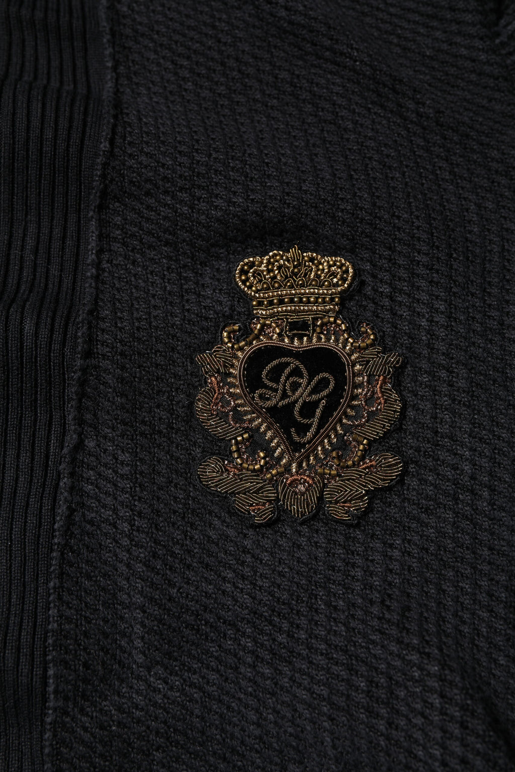Pull en soie noir Dolce & Gabbana avec boutons, motif héraldique élégant et détails raffinés visible sur l'image.