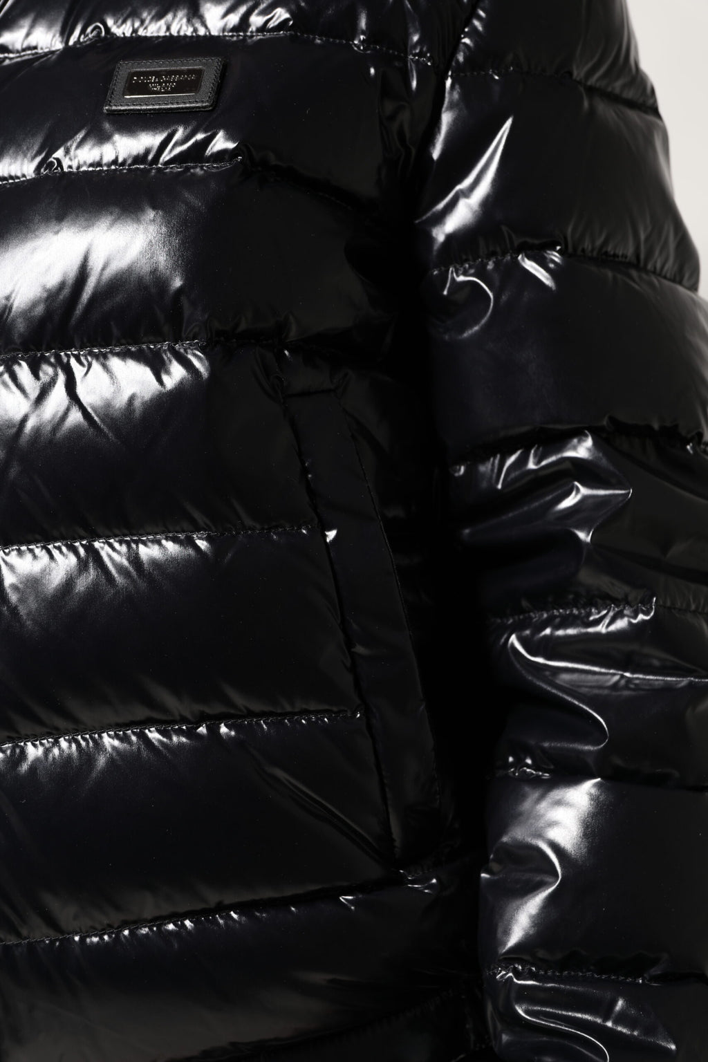 Veste matelassée noire Dolce & Gabbana avec logo en plaque, fermeture éclair intégrale, style puffer et design élégant.