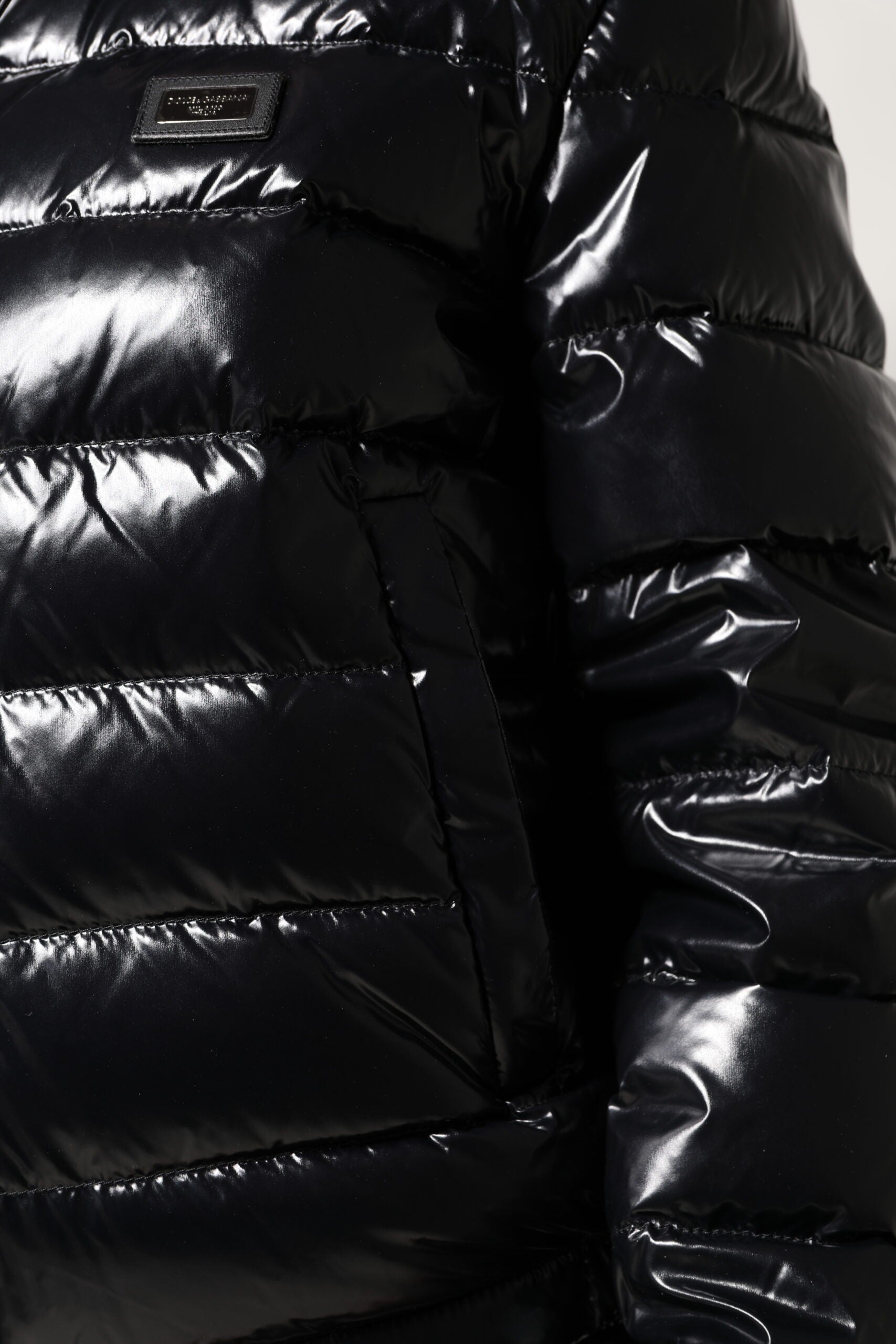 Veste matelassée noire Dolce & Gabbana avec logo en plaque, fermeture éclair intégrale, style puffer et design élégant.