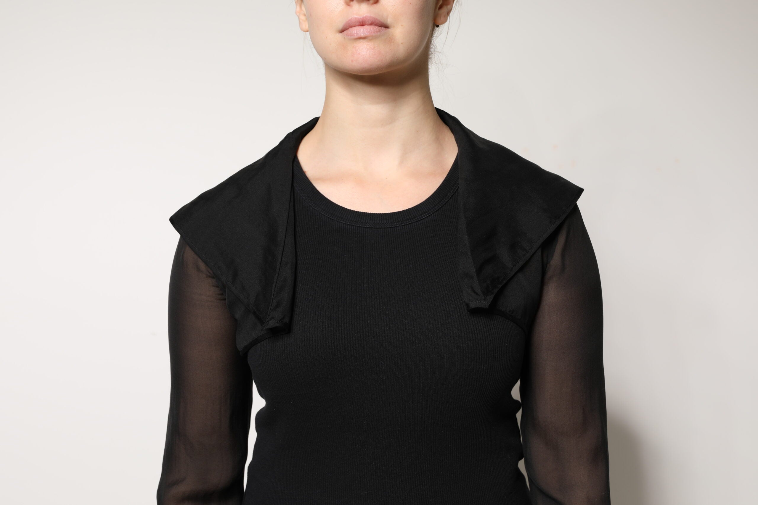 Blouse en soie noire à manches longues en dentelle transparente Dolce & Gabbana, élégante et raffinée, portée avec détails visibles.