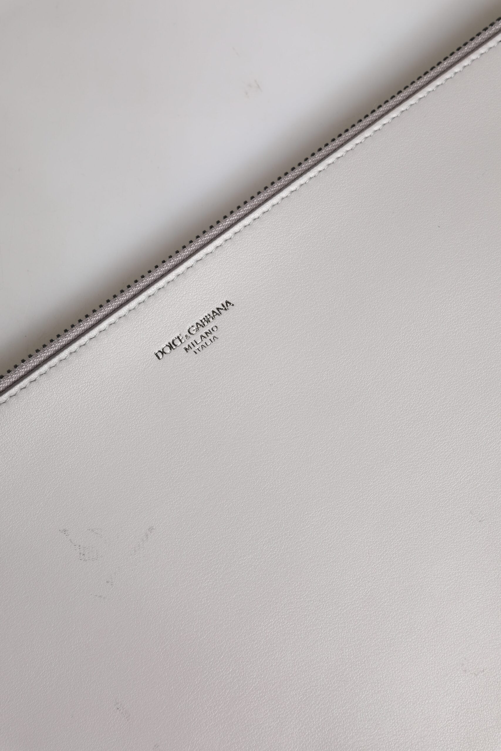 Pochette homme en cuir gris Dolce & Gabbana avec logo DG, fermoir zippé et design élégant.
