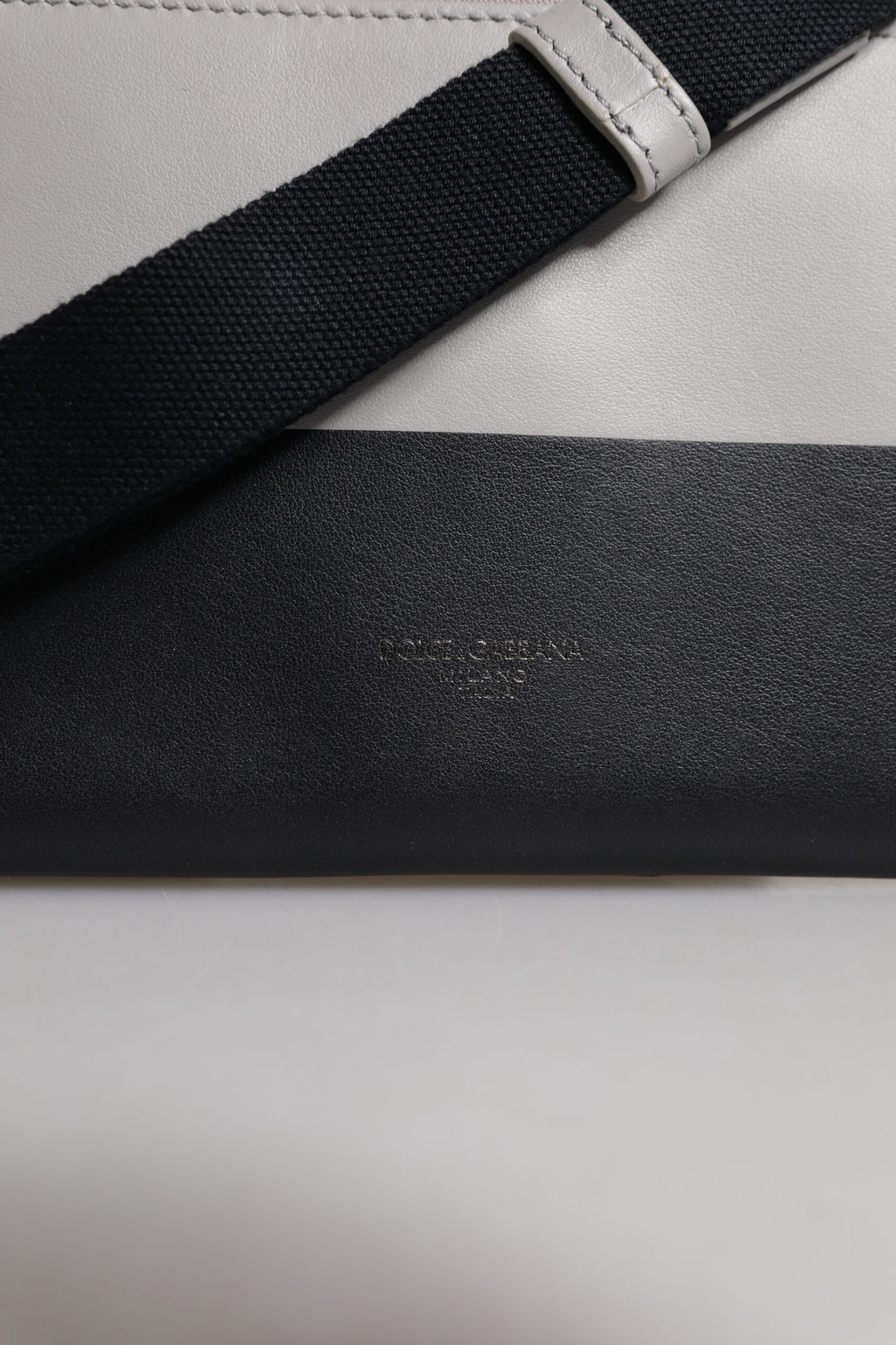 Sac à bandoulière en cuir noir et blanc Dolce & Gabbana avec logo embossé, design élégant et sophistiqué.