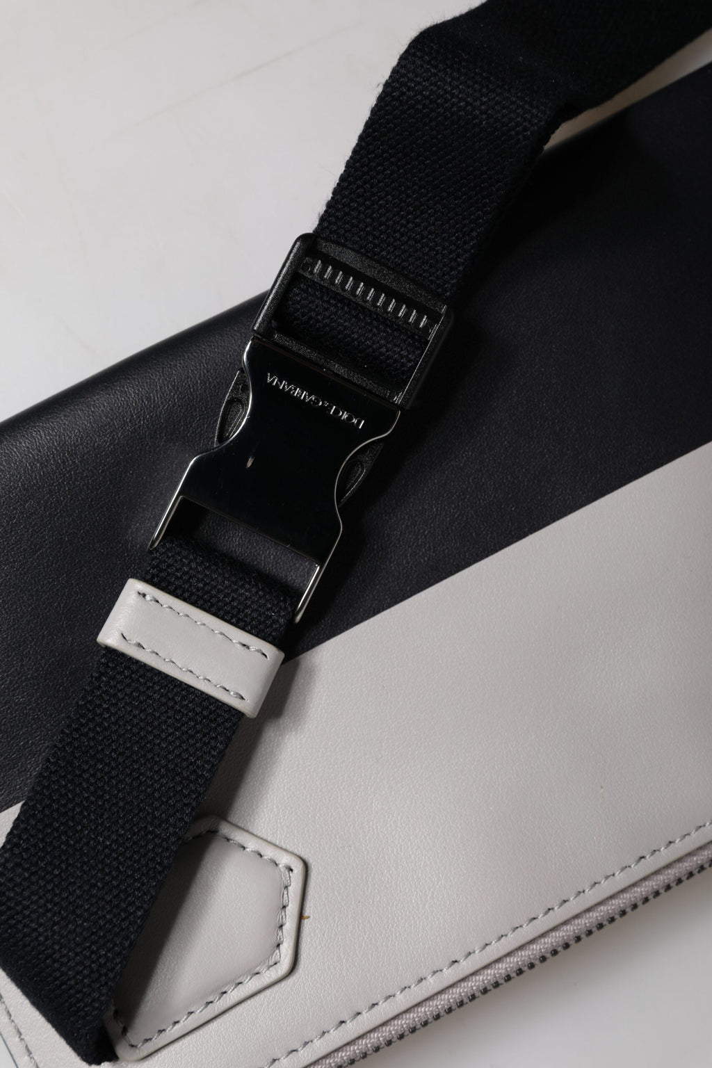 Sac à bandoulière en cuir noir et blanc Dolce & Gabbana avec logo embossé, élégant et sophistiqué.