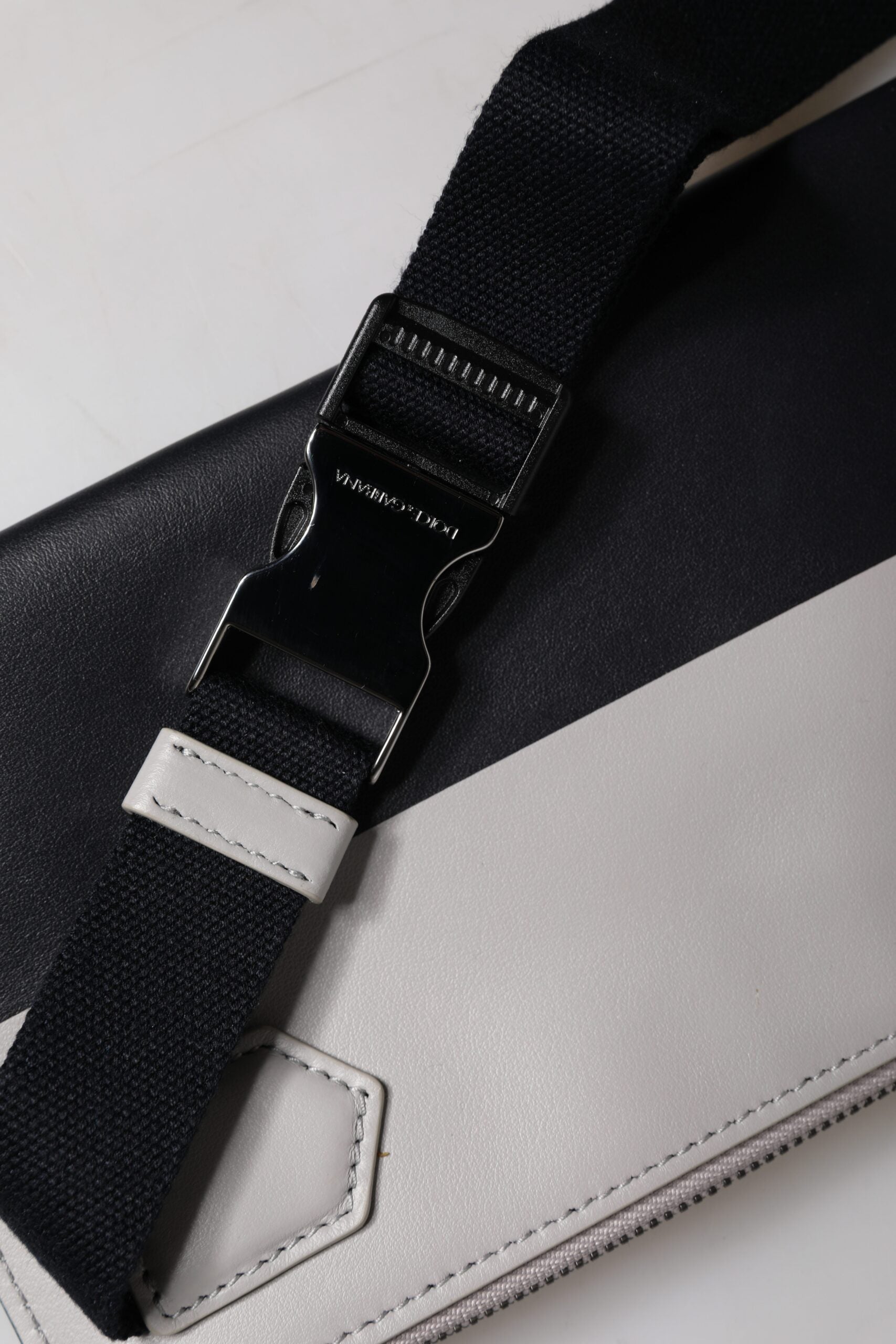 Sac à bandoulière en cuir noir et blanc Dolce & Gabbana avec logo embossé, élégant et sophistiqué.