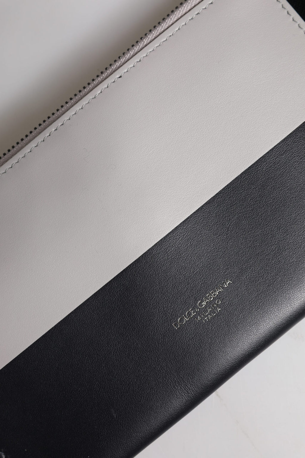 Sac bandoulière Dolce & Gabbana en cuir noir et blanc avec logo embossé, style élégant et moderne.
