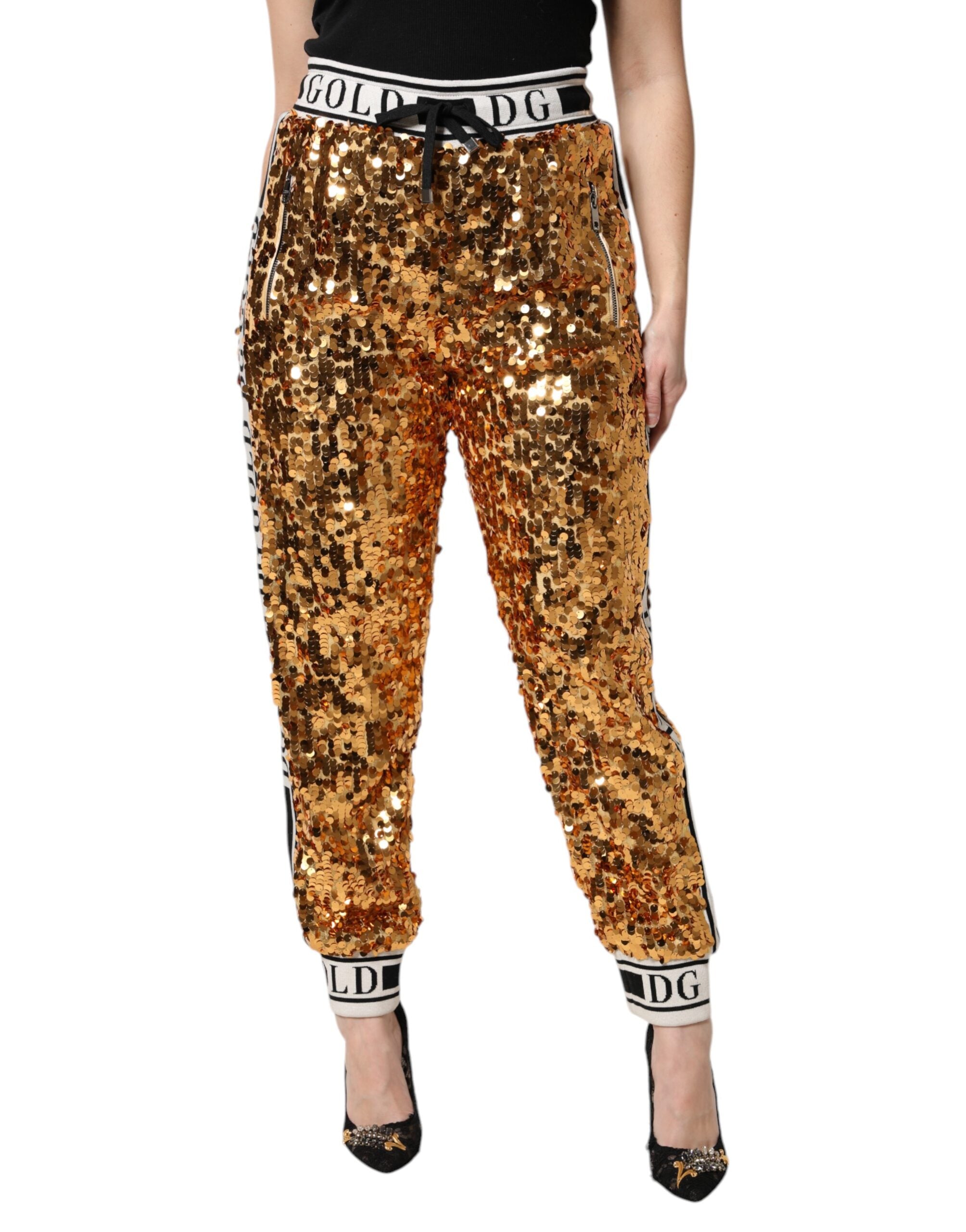 Pantalon jogger en sequins dorés métalliques avec logo Dolce & Gabbana en or, style chic et décontracté.