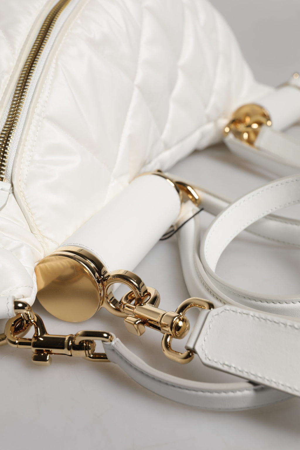 Sac banane Dolce & Gabbana blanc avec logo en relief, en tissu matelassé et plaque emblématique, porté à la taille.