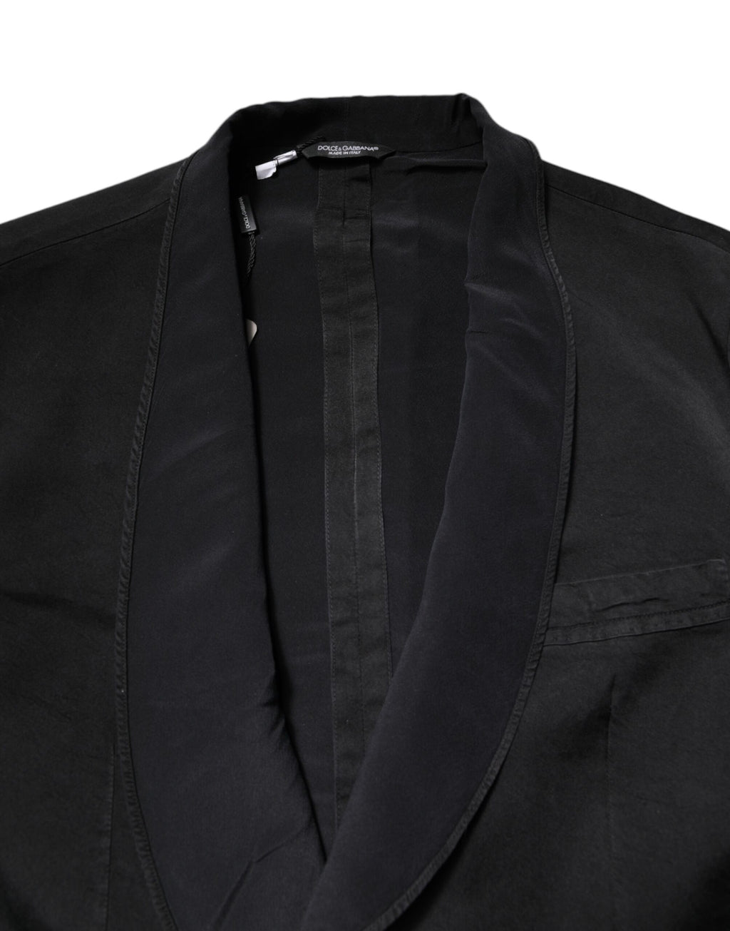 Manteau blazer en soie noire Dolce & Gabbana, coupe simple, à double boutonnage, porté sur un fond neutre.