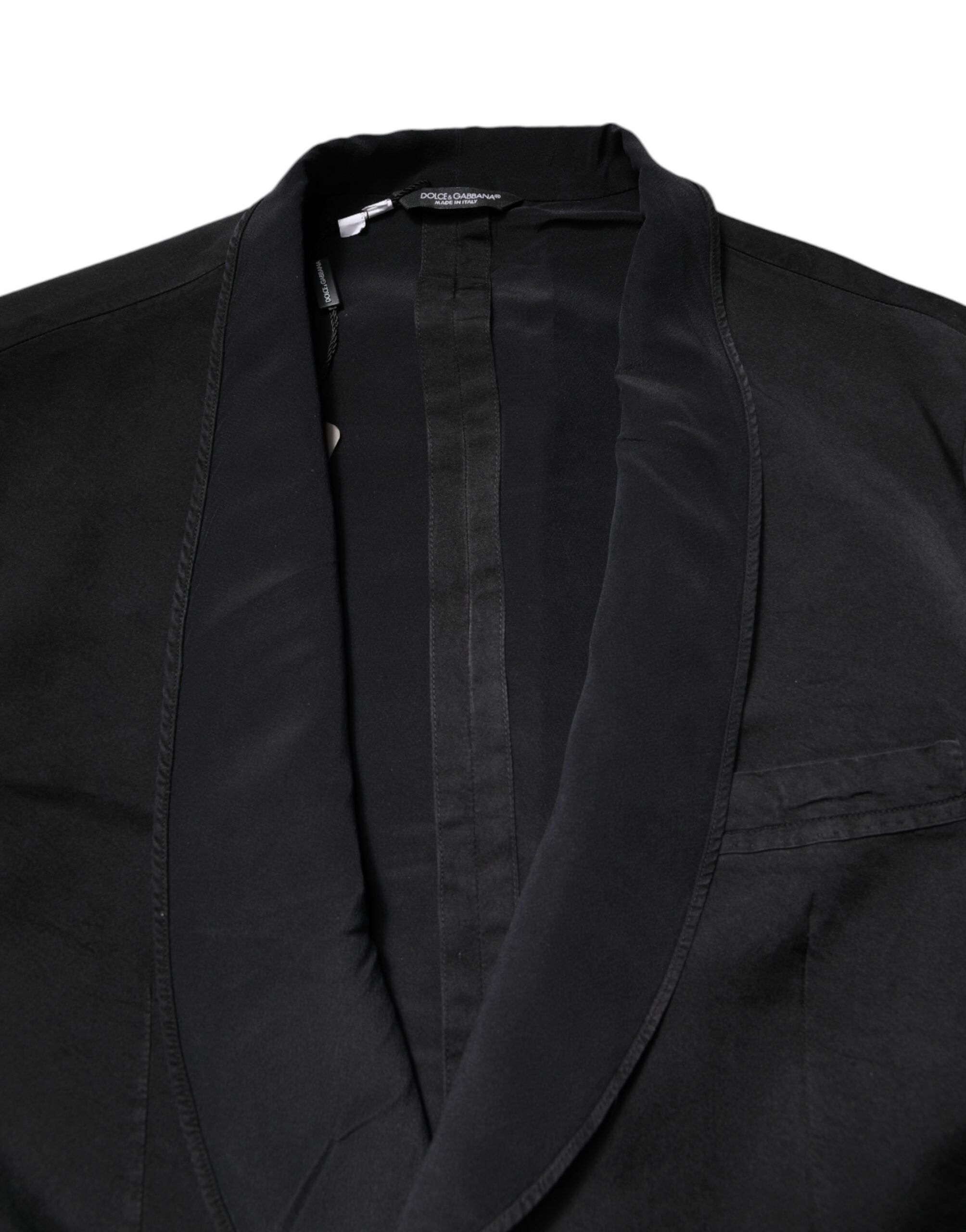 Manteau blazer en soie noire Dolce & Gabbana, coupe simple, à double boutonnage, porté sur un fond neutre.