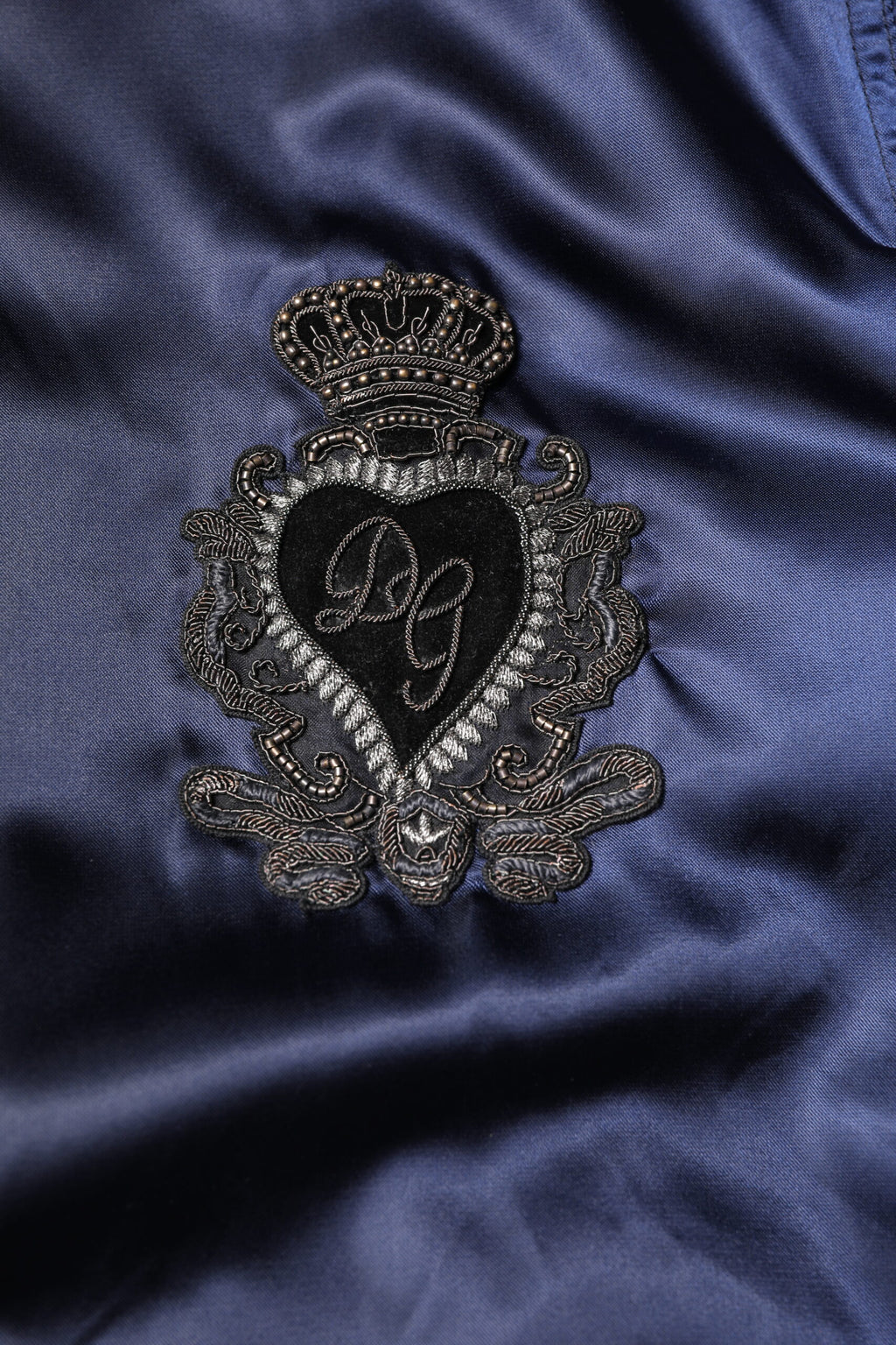 Veste bomber zippée en nylon bleu Dolce & Gabbana avec logo DG et motif couronne, style moderne et élégant.