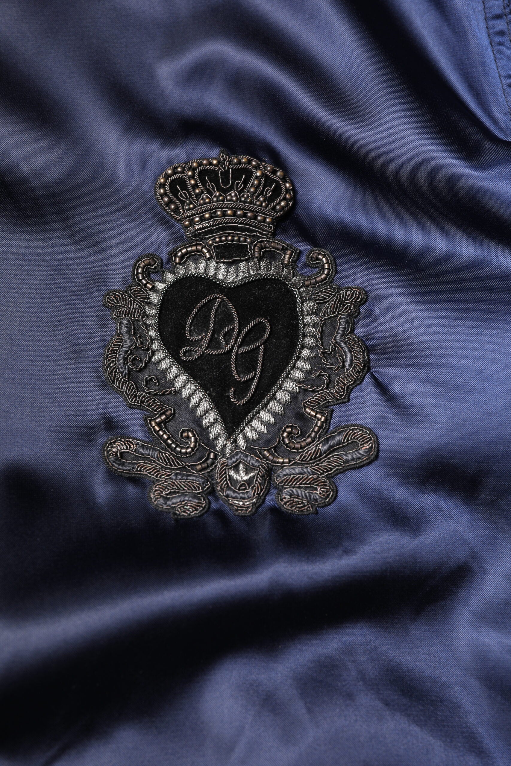 Veste bomber zippée en nylon bleu Dolce & Gabbana avec logo DG et motif couronne, style moderne et élégant.