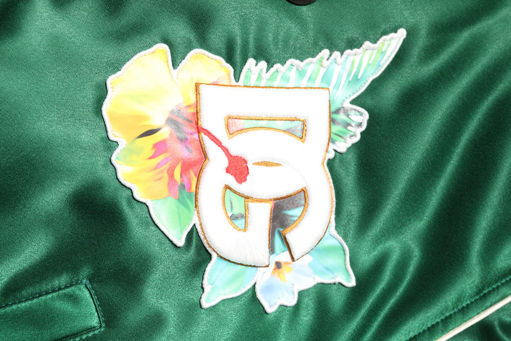 Veste bomber Dolce & Gabbana vert avec logo DG floral, zip complet et design élégant, visible sur l'image.