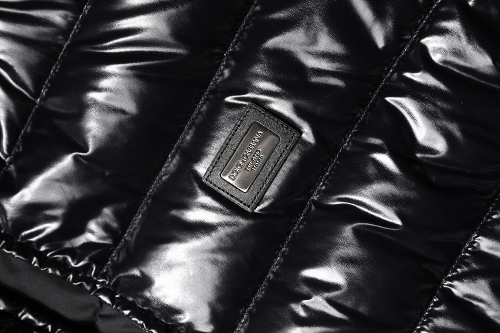 Veste matelassée noire Dolce & Gabbana avec logo en plaque, fermeture éclair intégrale, style chaud et tendance.