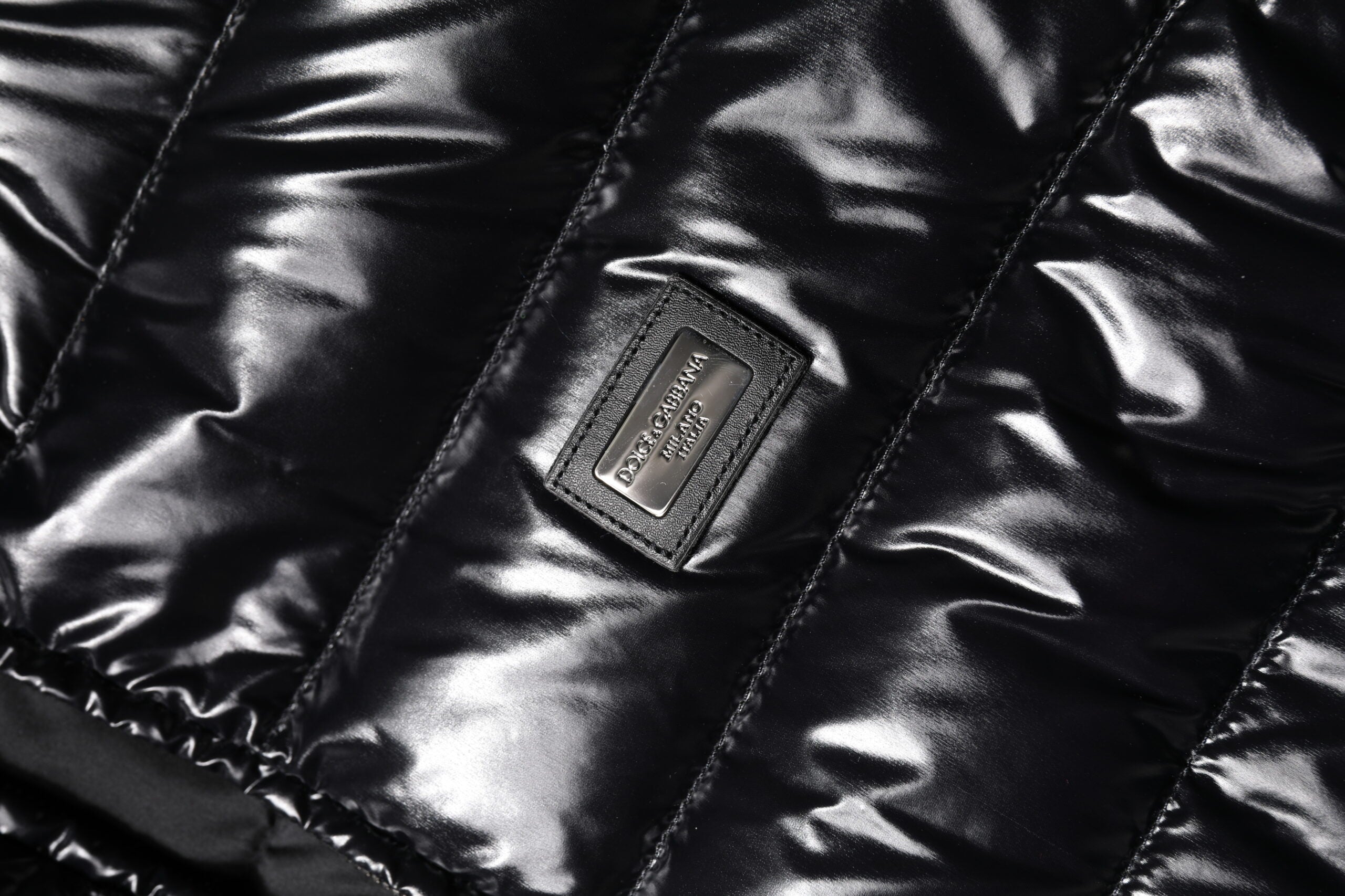 Veste matelassée noire Dolce & Gabbana avec logo en plaque, fermeture éclair intégrale, style chaud et tendance.
