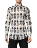 Chemise longue blanche Dolce & Gabbana avec imprimé ananas doré et manches longues, style élégant et tropical.