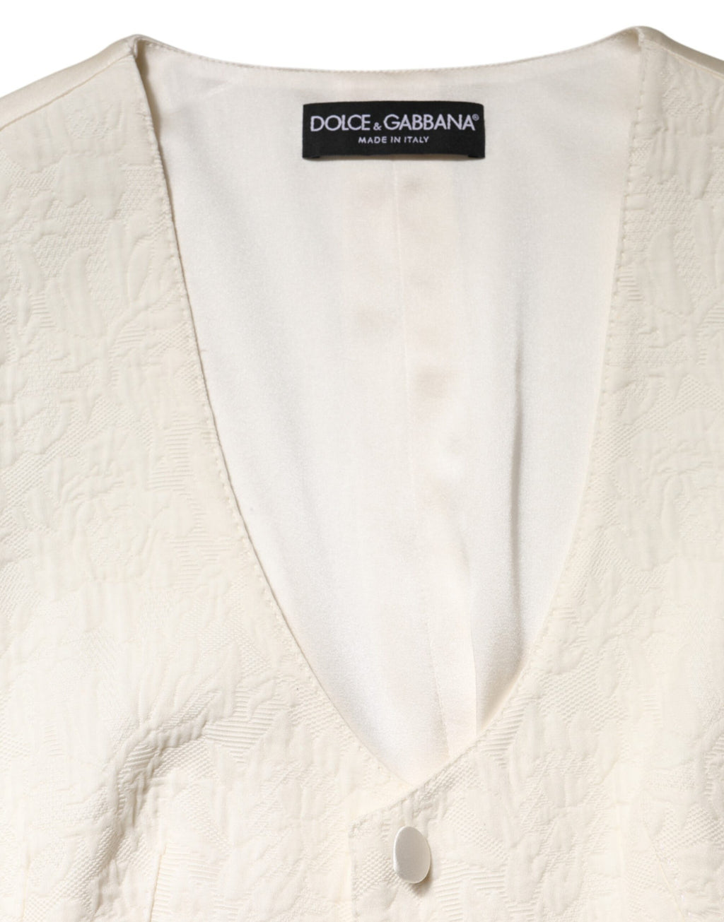 Gilet sans manches en coton ivoire de Dolce & Gabbana, boutonnière, élégant et léger, porté sur un fond neutre.