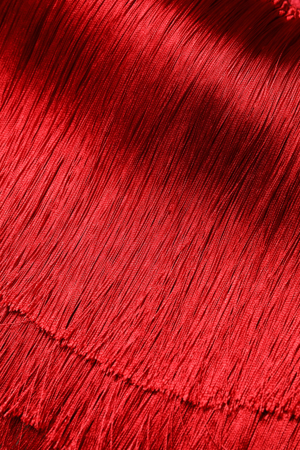 Top crop en soie rouge sans bretelles avec franges, de la marque Dolce & Gabbana, visible en détail dans l'image.