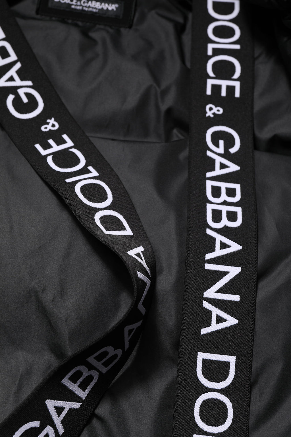 Veste matelassée noire à capuche avec logo Dolce & Gabbana, fermeture éclair complète, style chic et décontracté.