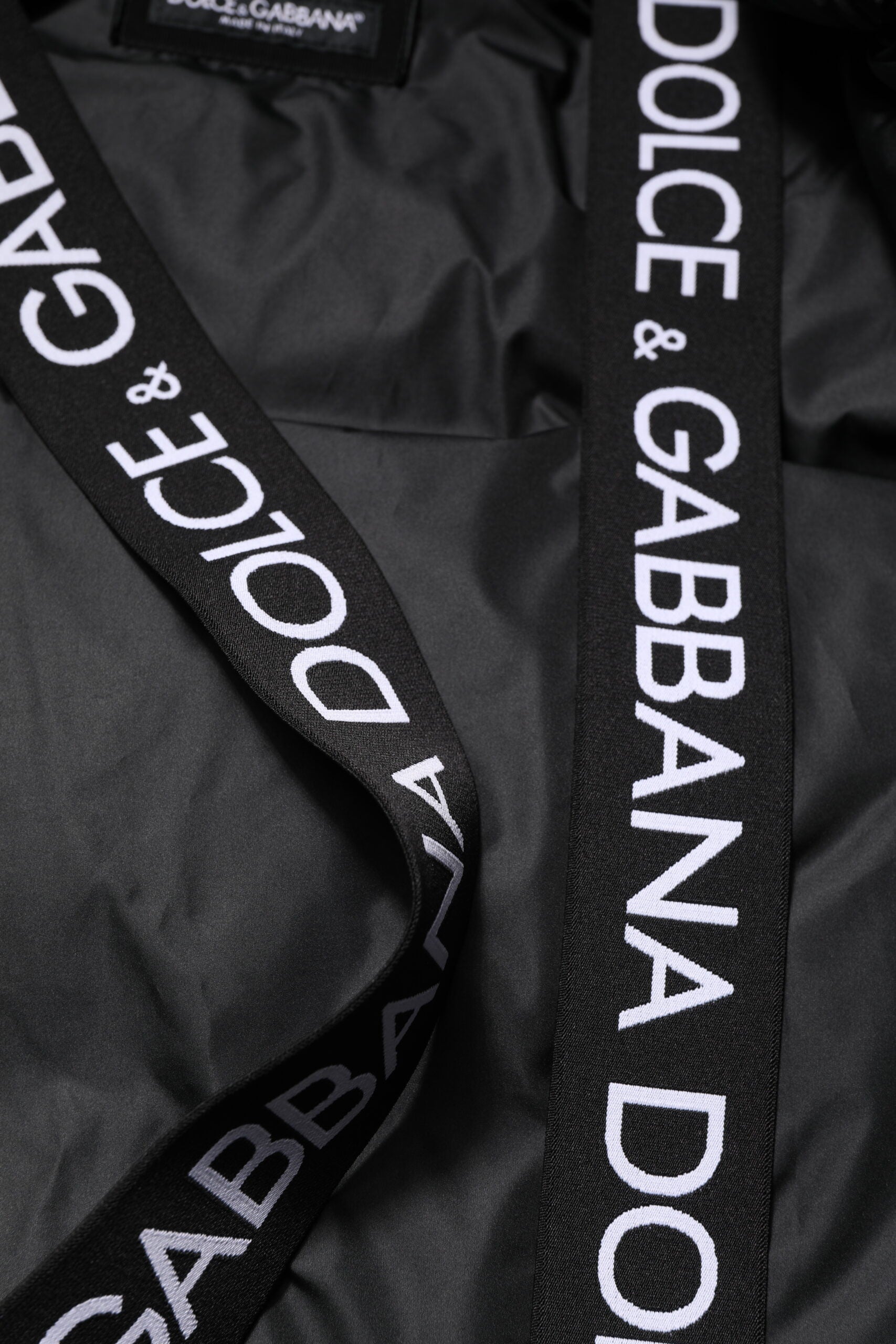Veste matelassée noire à capuche avec logo Dolce & Gabbana, fermeture éclair complète, style chic et décontracté.