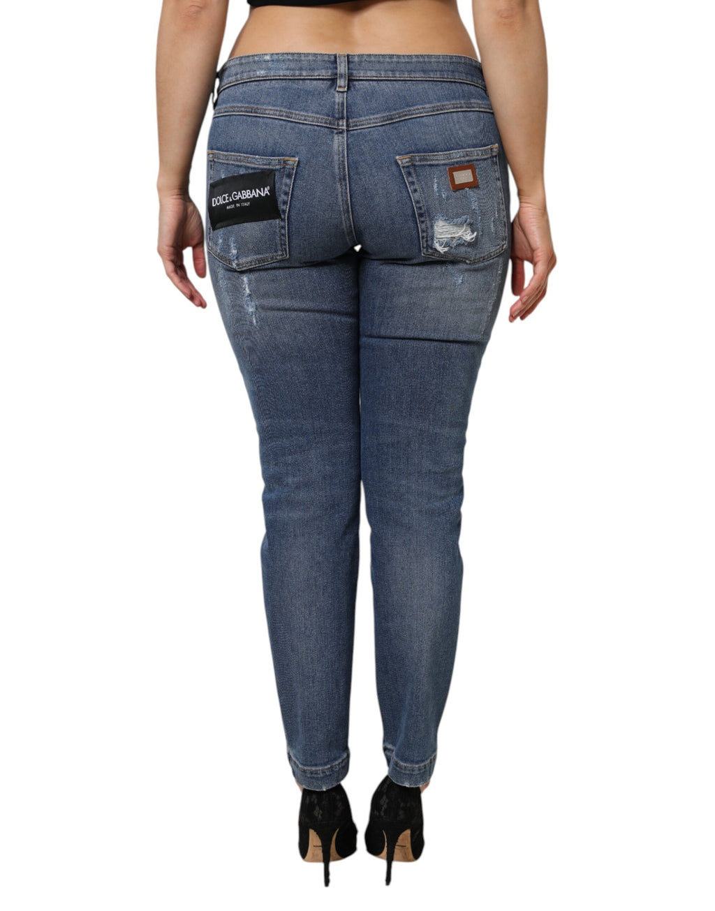 Jeans en denim bleu Dolce & Gabbana, déchirés, à taille basse, visible en détail sur l'image.