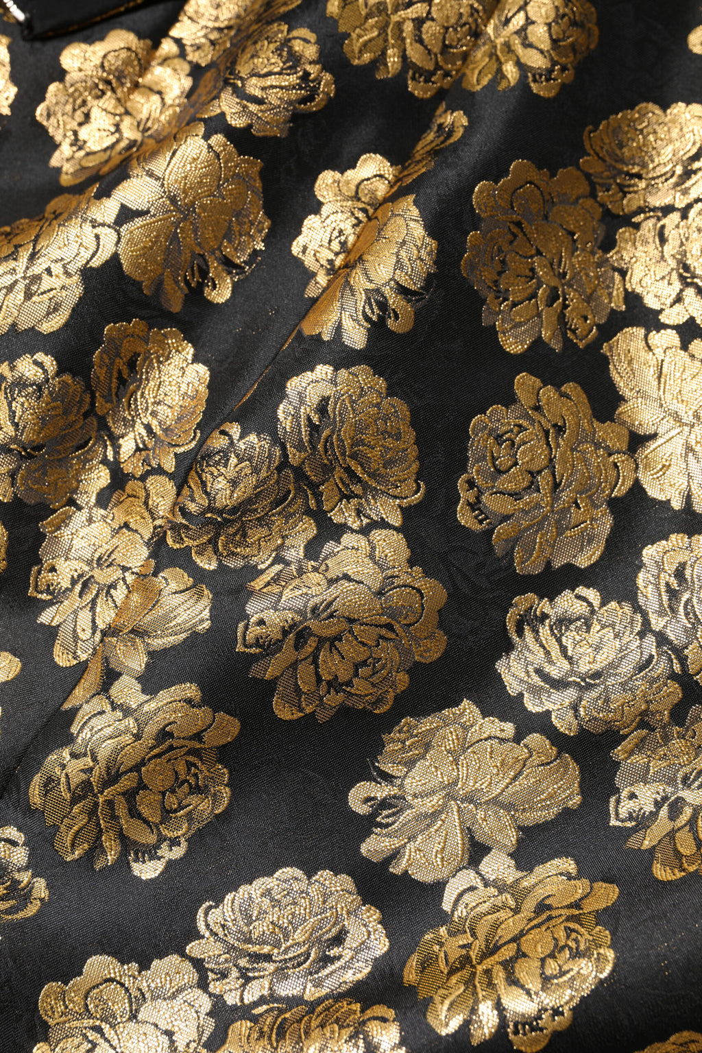 Mini jupe en jacquard noir et or à motif floral de Dolce & Gabbana, visible avec détails élégants et texture riche.