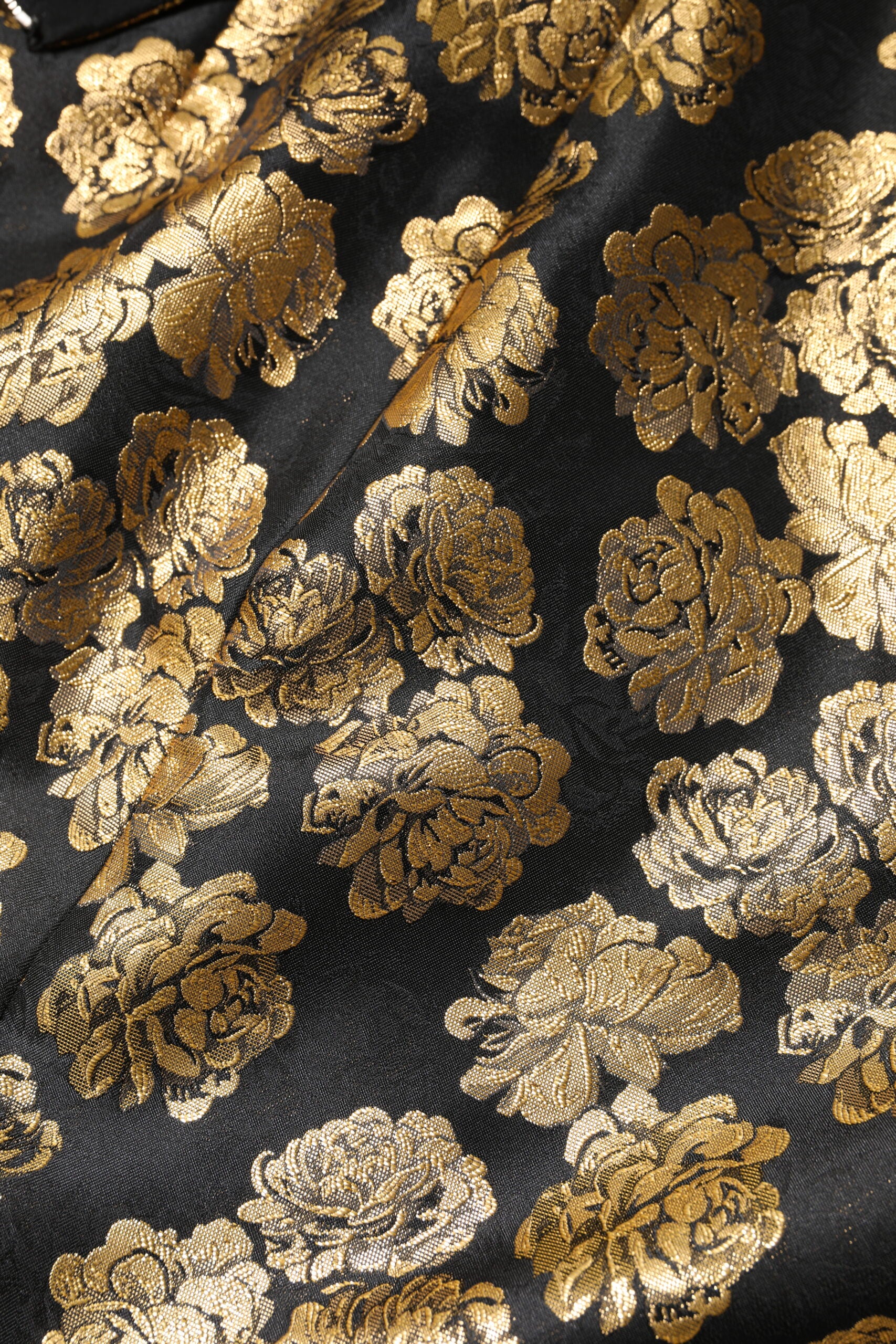 Mini jupe en jacquard noir et or à motif floral de Dolce & Gabbana, visible avec détails élégants et texture riche.