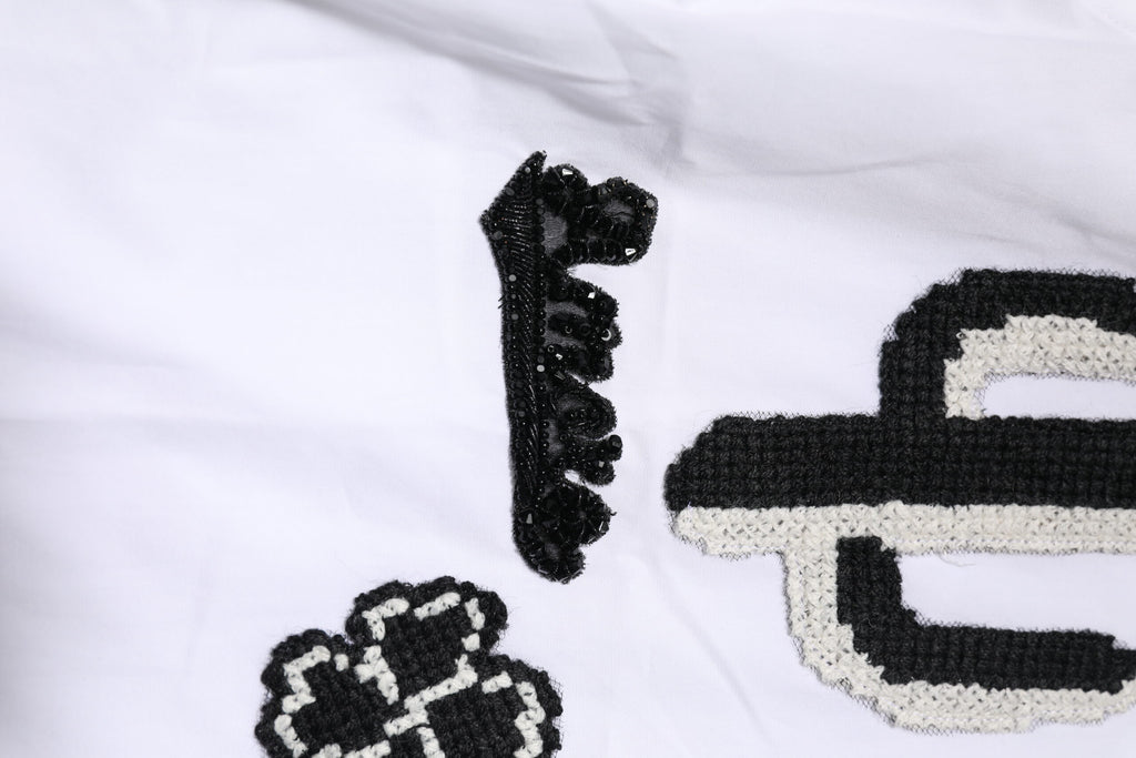 Chemise blanche Dolce & Gabbana avec broderie dorée et détails élégants, en tissu finement travaillé.