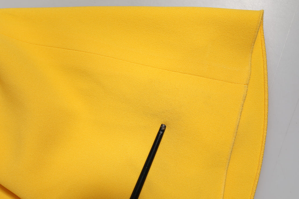 Robe élégante jaune à une épaule avec fente latérale, de la marque Dolce & Gabbana, portée sur un mannequin.