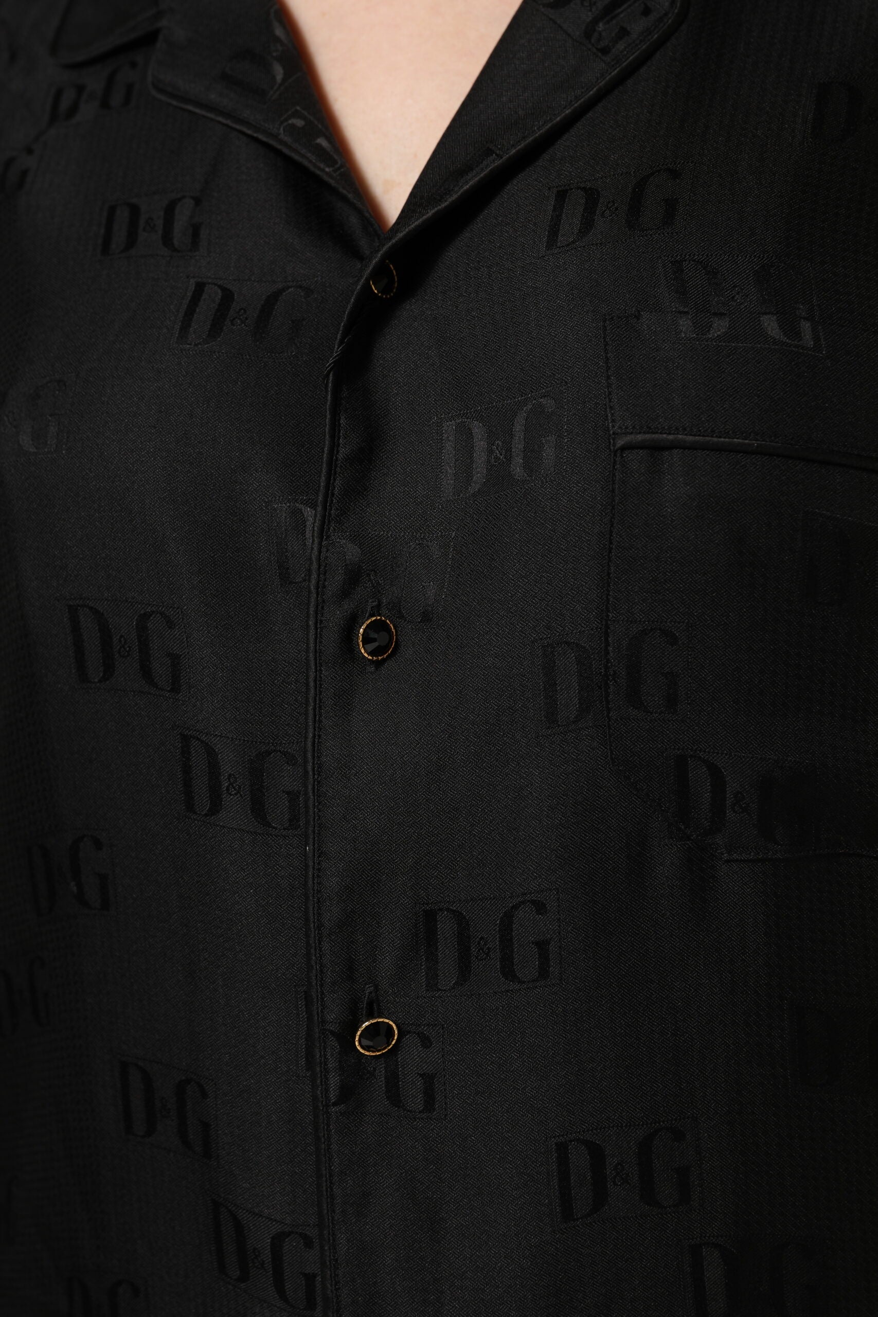Chemise longue en soie noire Dolce & Gabbana avec broderies DG et manches longues, élégante et raffinée.
