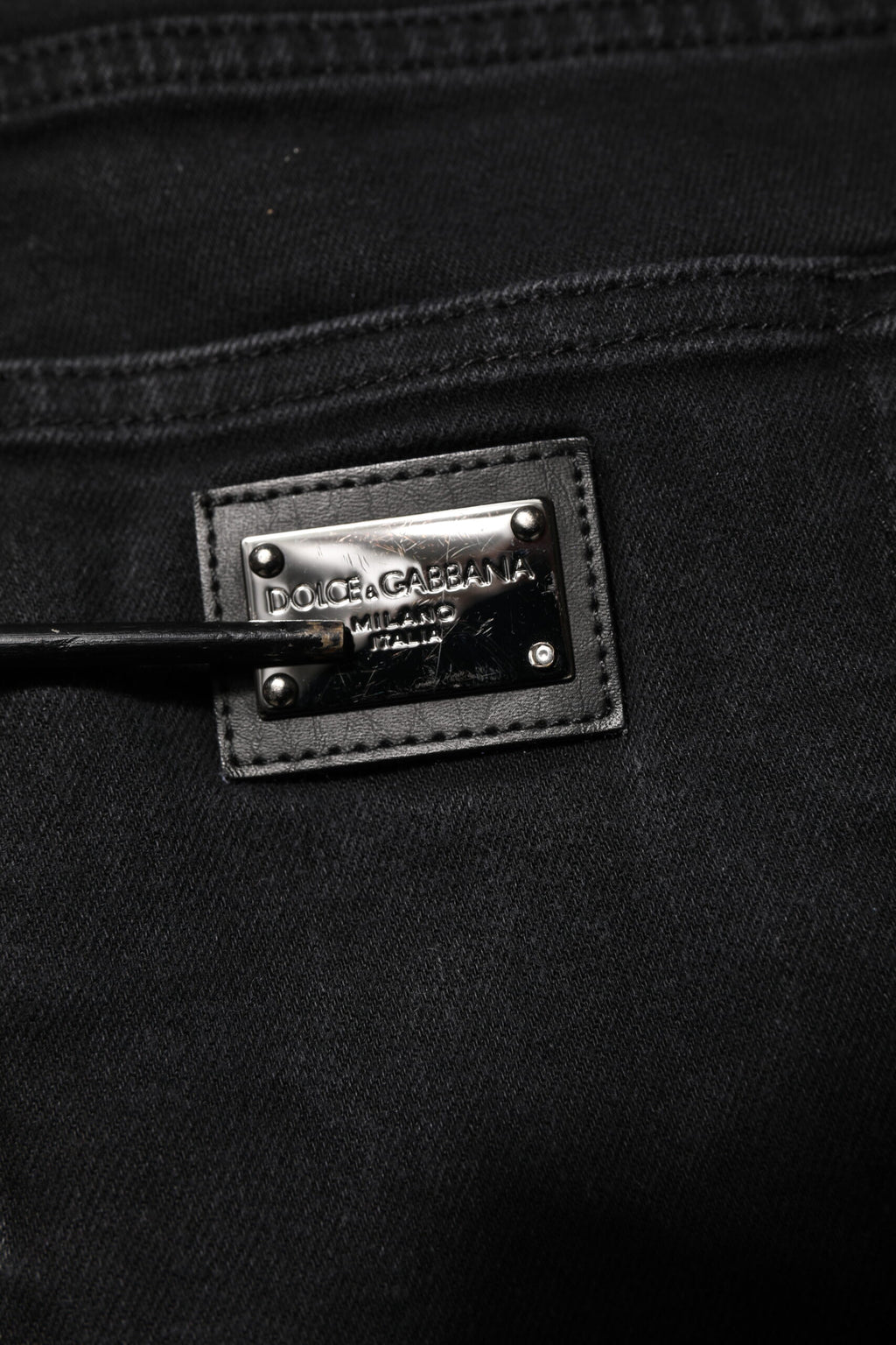 Jeans slim en coton noir Dolce & Gabbana avec plaque logo, finition élégante et coupe ajustée, visible sur l'image.