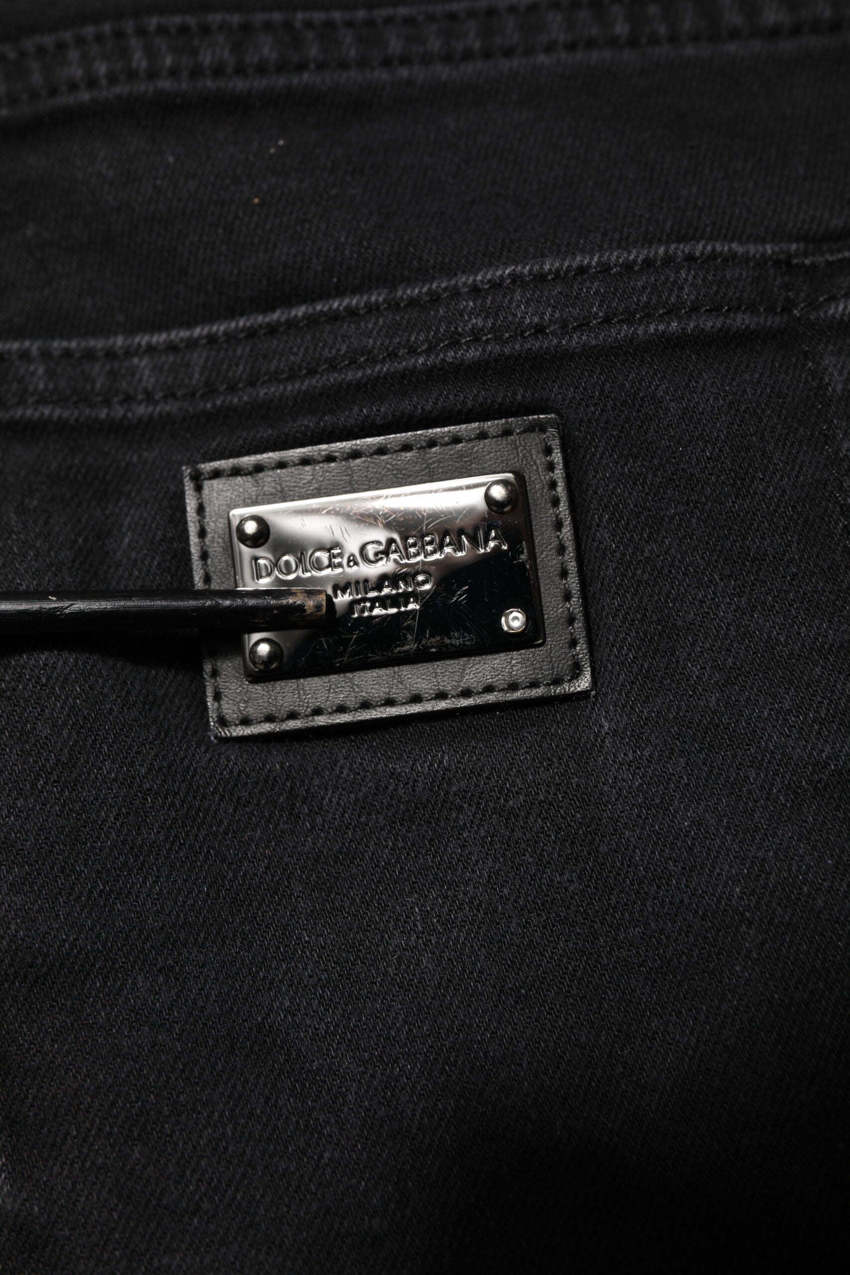 Jeans slim en coton noir Dolce & Gabbana avec plaque logo, finition élégante et coupe ajustée, visible sur l'image.