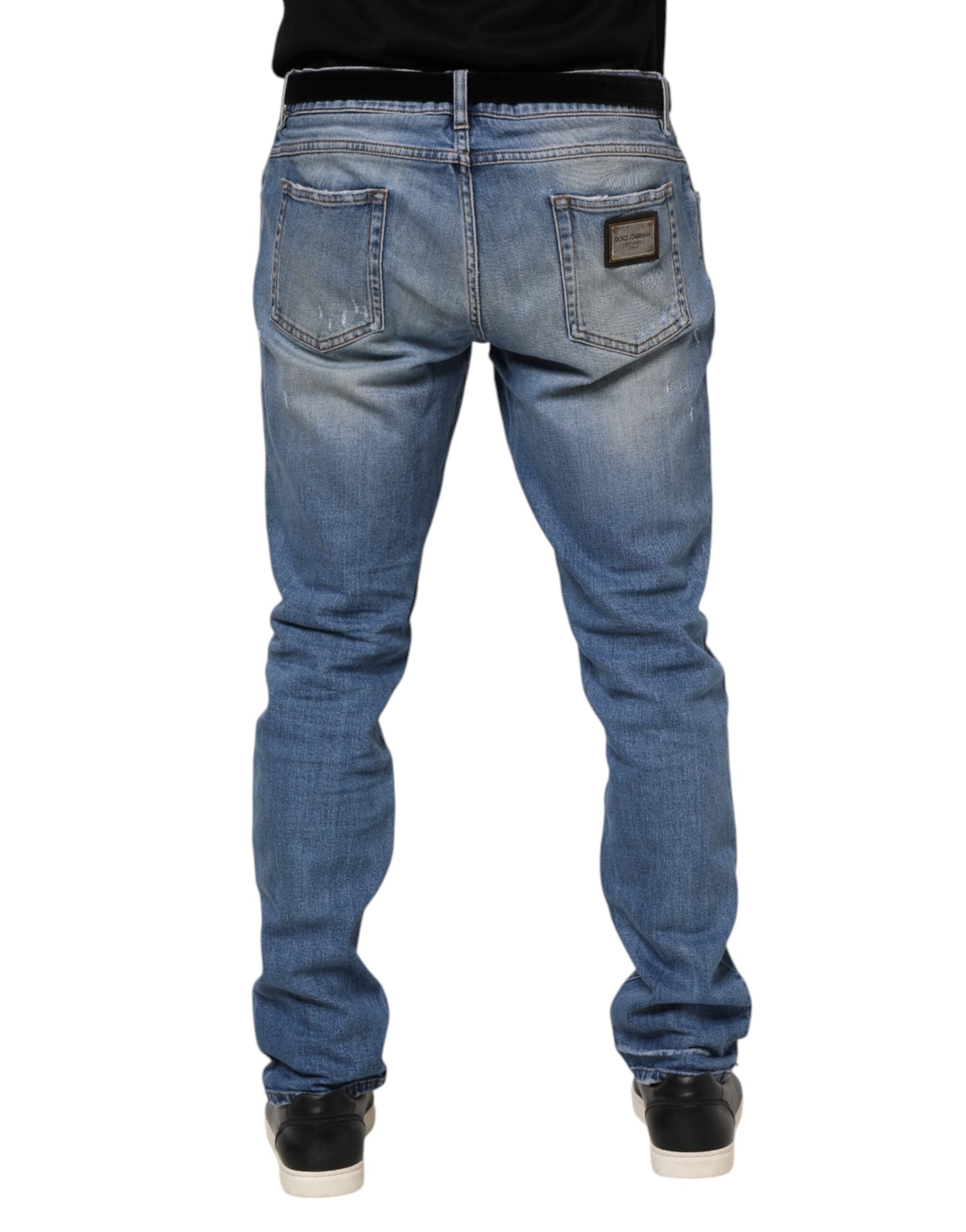 Jeans en denim bleu délavé Dolce & Gabbana avec déchirures, plaque logo tissée et style décontracté.