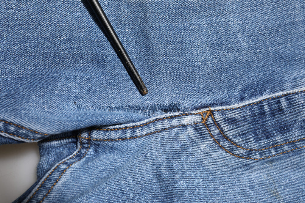 Jeans en denim bleached Dolce & Gabbana avec logo, déchirures et plaque en tissage vintage, mode urbaine élégante.