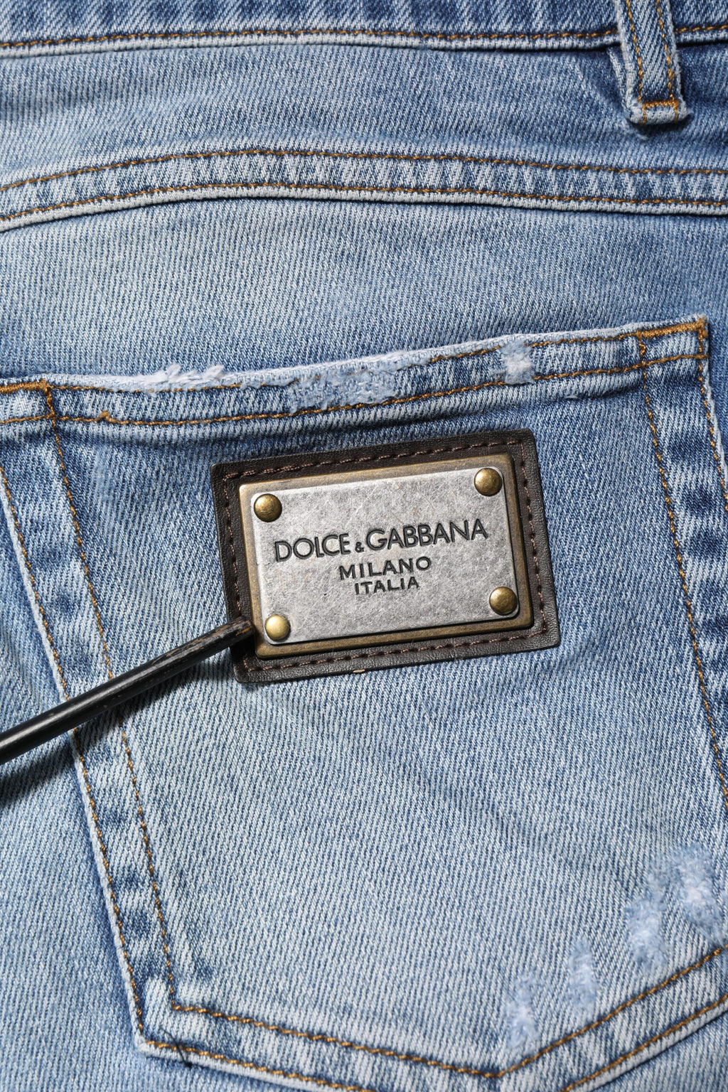 Jeans en denim bleu Dolce & Gabbana avec logo, ourlet déchiré et aspect vintage, style décontracté et tendance.