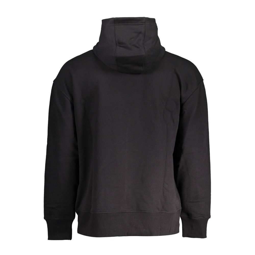 Pull homme en coton noir Tommy Hilfiger, col rond, look décontracté, porté avec jeans.
