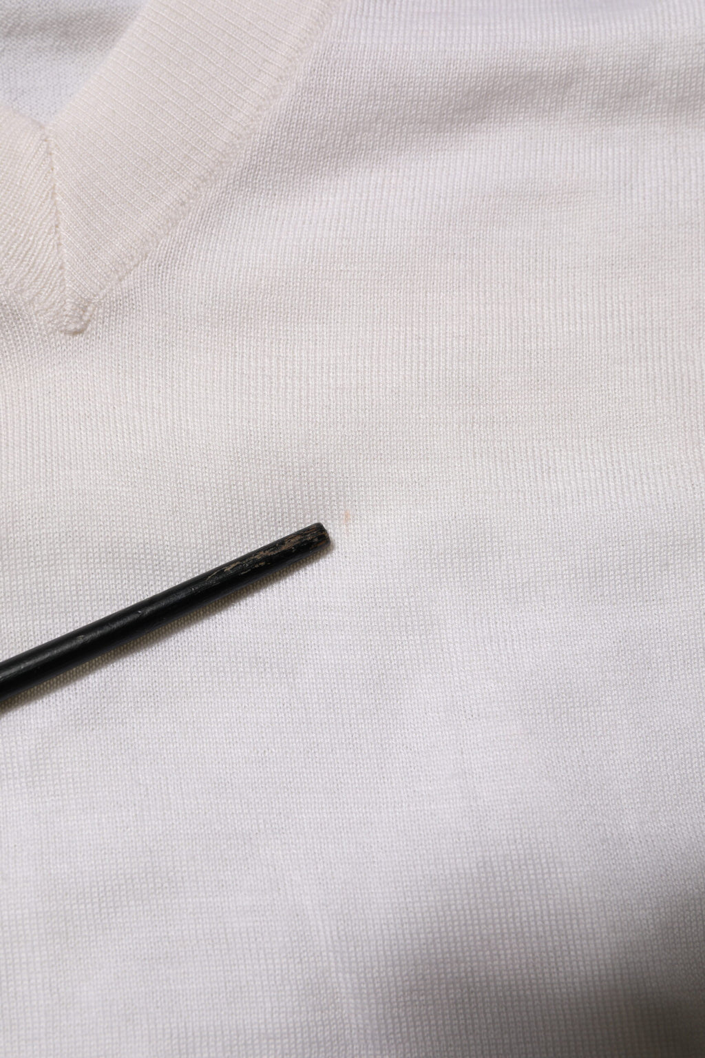 Pull en cachemire blanc Dolce & Gabbana à logo V-neck, doux et élégant, visible détail du col en V et texture du tissu.