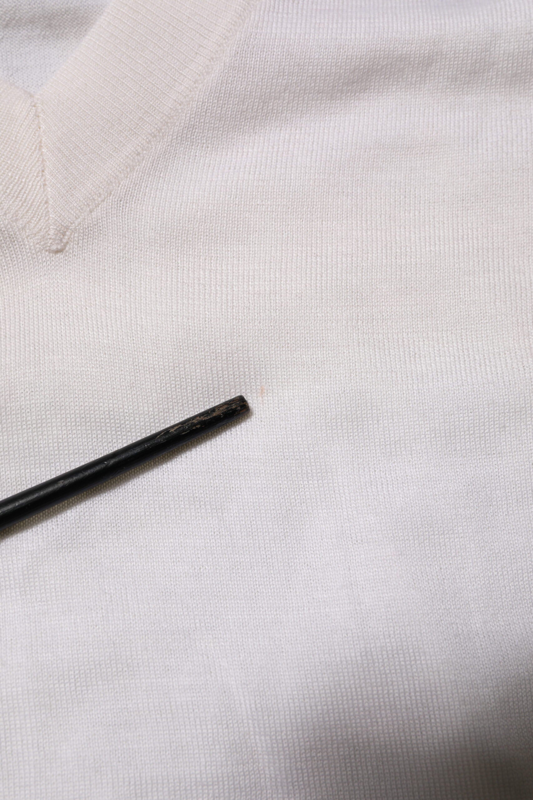 Pull en cachemire blanc Dolce & Gabbana à logo V-neck, doux et élégant, visible détail du col en V et texture du tissu.