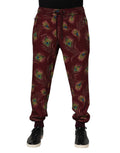 Pantalons jogger Dolce & Gabbana en velours bordeaux avec motif plumes de paon, style décontracté et élégant.
