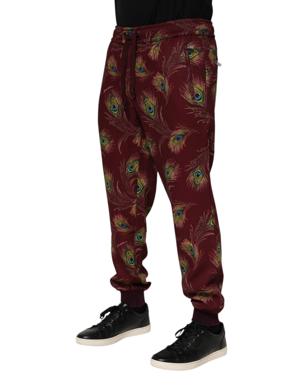 Pantalons joggers Dolce & Gabbana en velours bordeaux avec motif plumes de paon, coupe décontractée et détails élégants.
