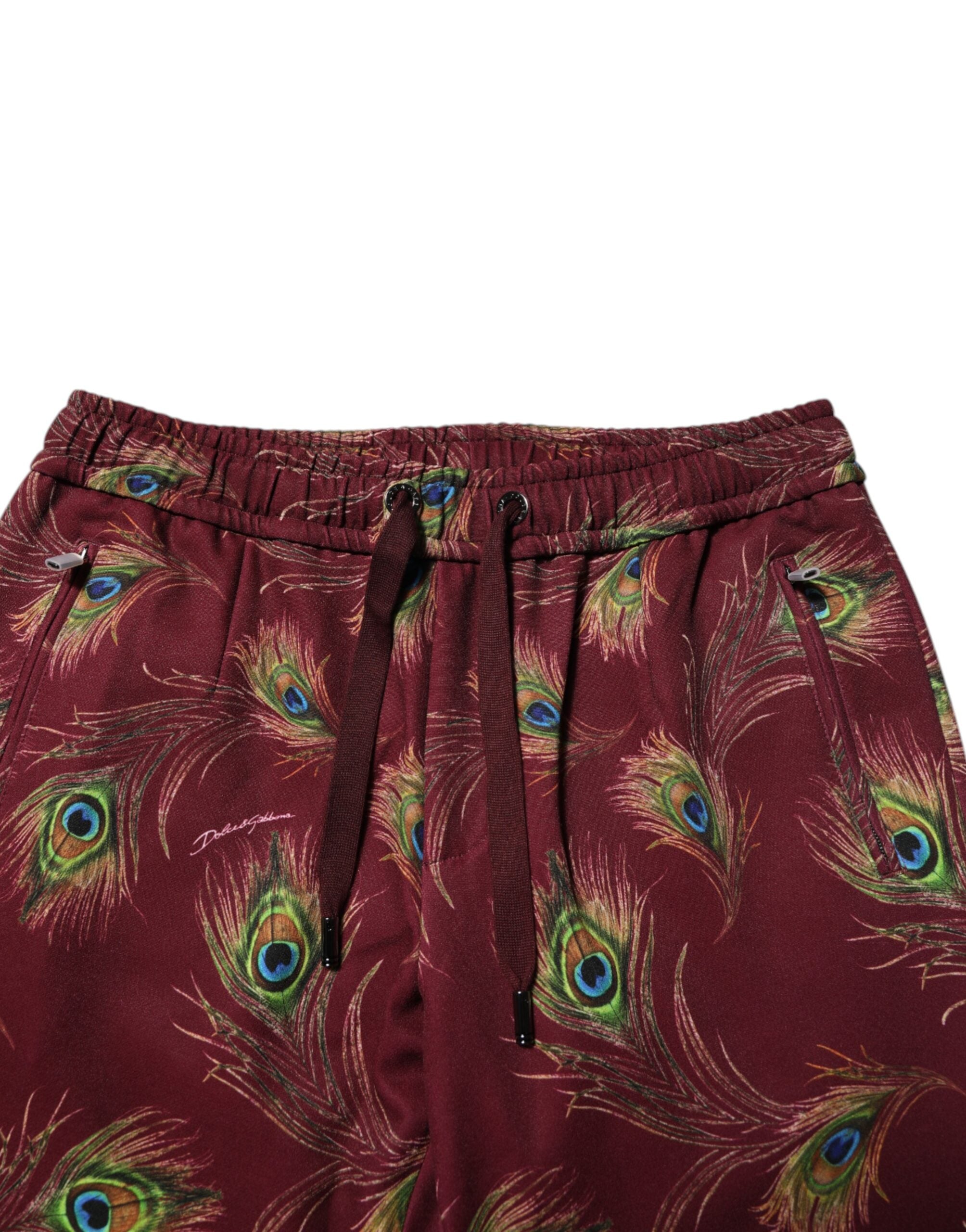 Pantalons jogger Dolce & Gabbana en tissu bordeaux avec motif plumes de paon, style élégant et décontracté.