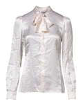 Chemisier blanc à col ascot à manches longues de Dolce & Gabbana, élégant et sophistiqué, visible avec détails en tissu.