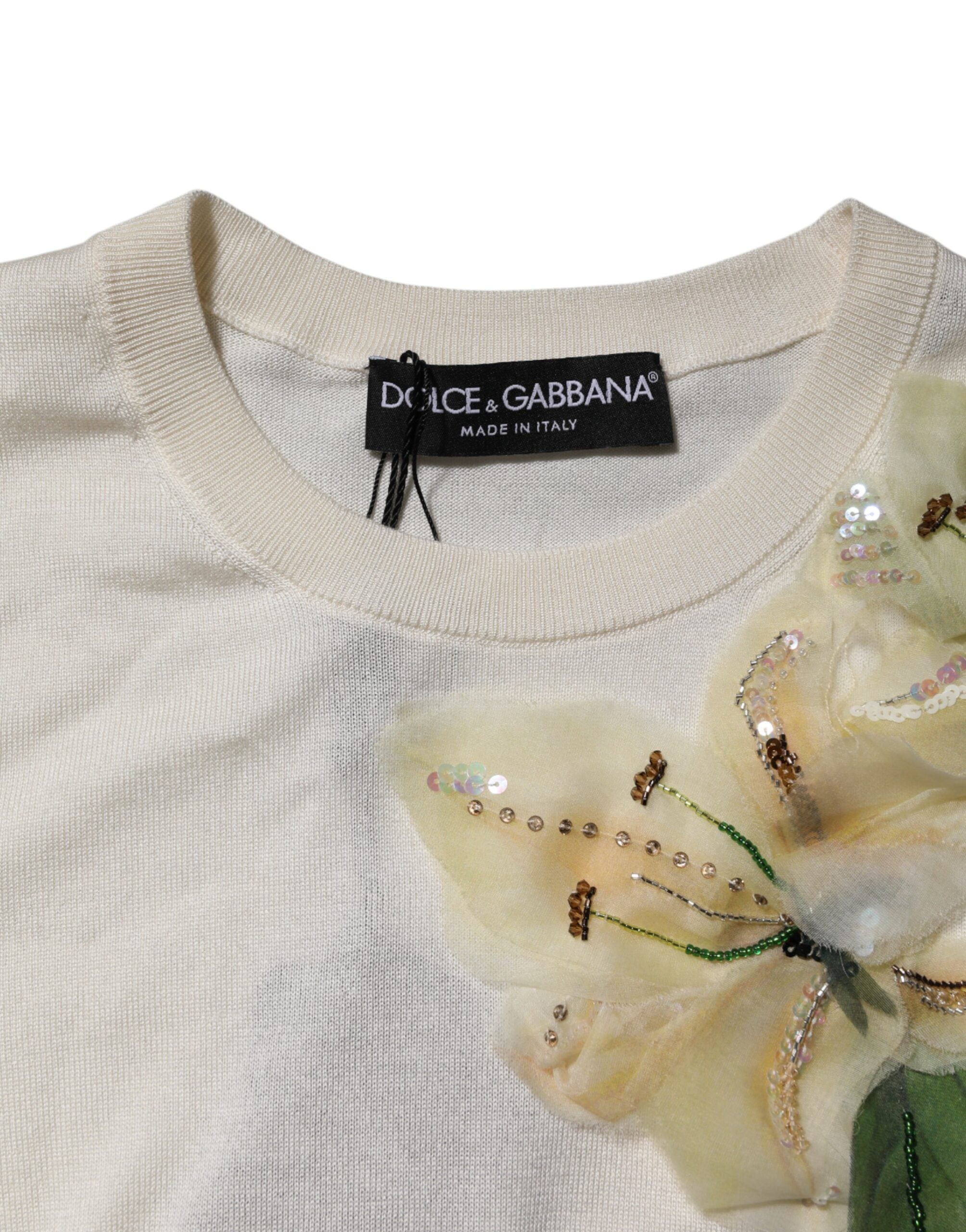 Pull-over Dolce & Gabbana en soie blanche avec embellissements de lys, style élégant et sophistiqué, visible avec détails floraux.