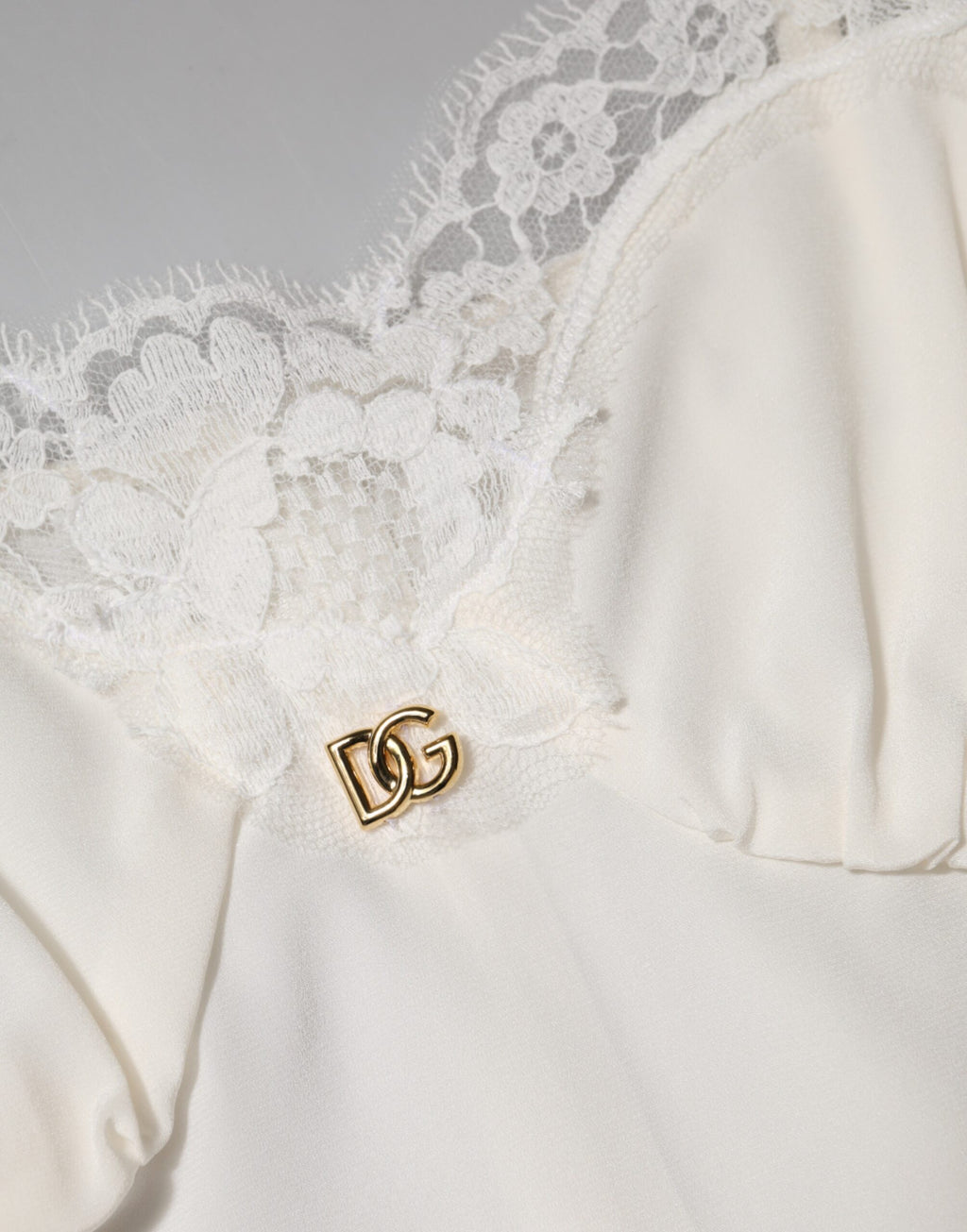 Robe de nuit en soie blanche Dolce & Gabbana avec dentelle, logo doré DG et détails élégants.