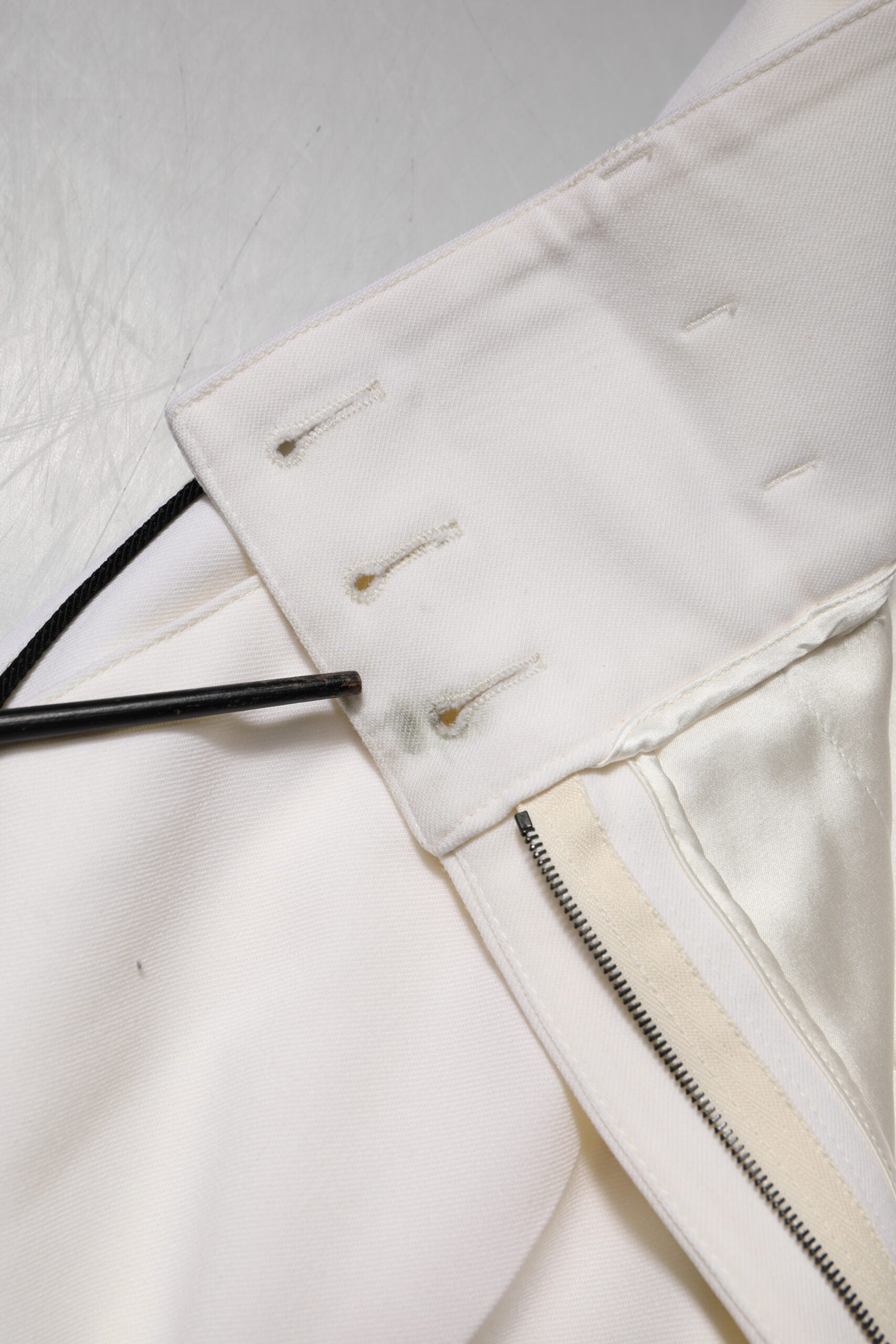 Pantalons en laine blanche à taille haute et coupe tapered de Dolce & Gabbana, visibles sur l'image.