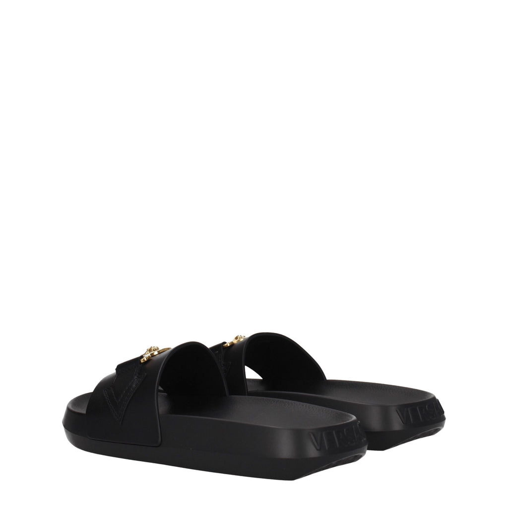 Chaussons en cuir noir de marque Versace, style élégant et confortable, avec logo distinctif visible sur la chaussure.