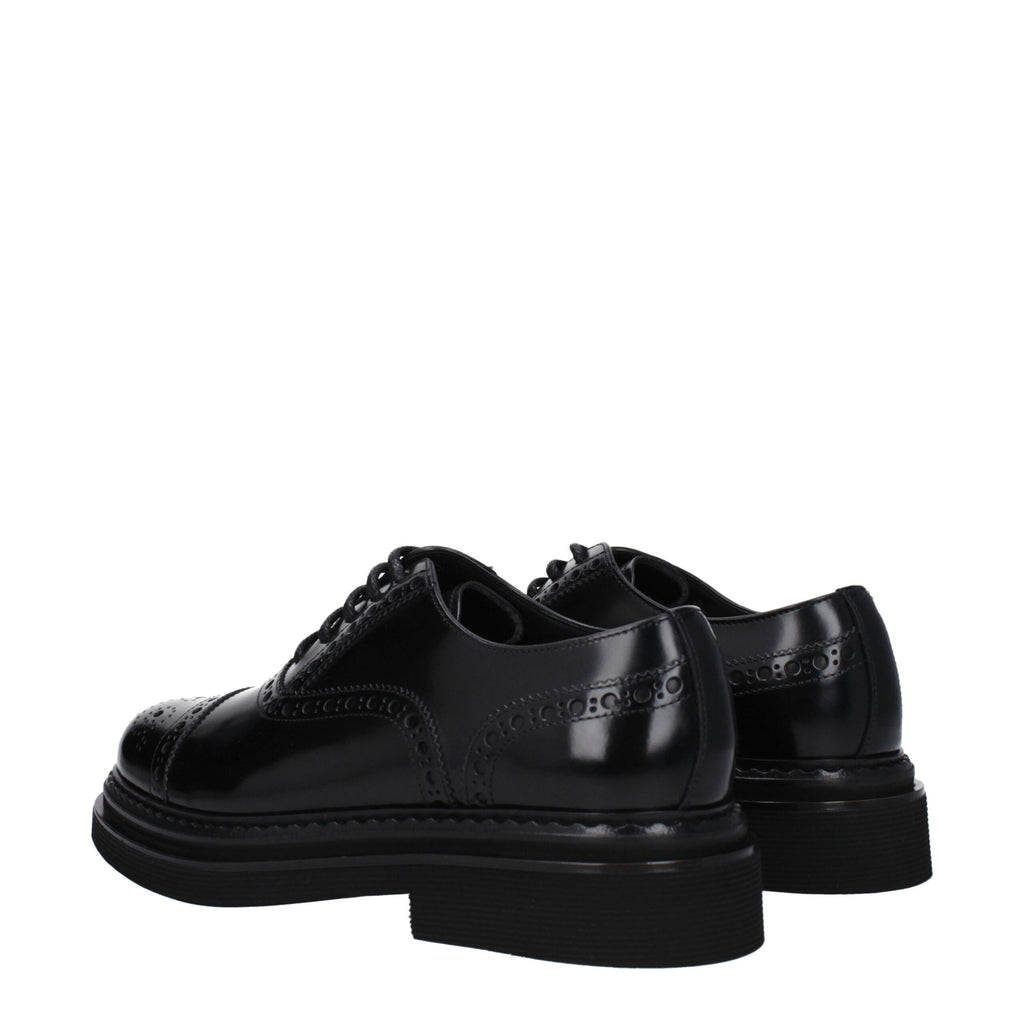 Chaussures Oxford et derby en cuir noir de Dolce & Gabbana, élégantes et classiques, près d'une surface blanche.